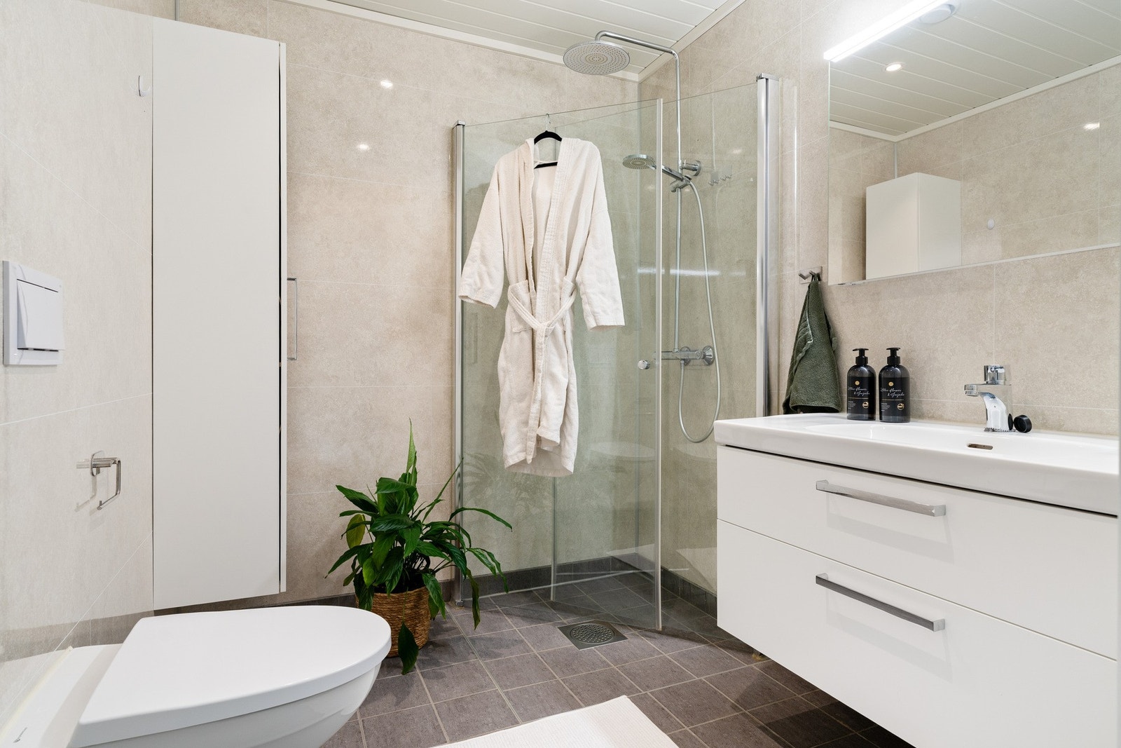 Innbydende baderom på 4 kvm med flis på gulv og vannbåren gulvvarme. TG1. Avtrekk via balansert ventilasjon. Innredning fra Fossline. Galleribilde