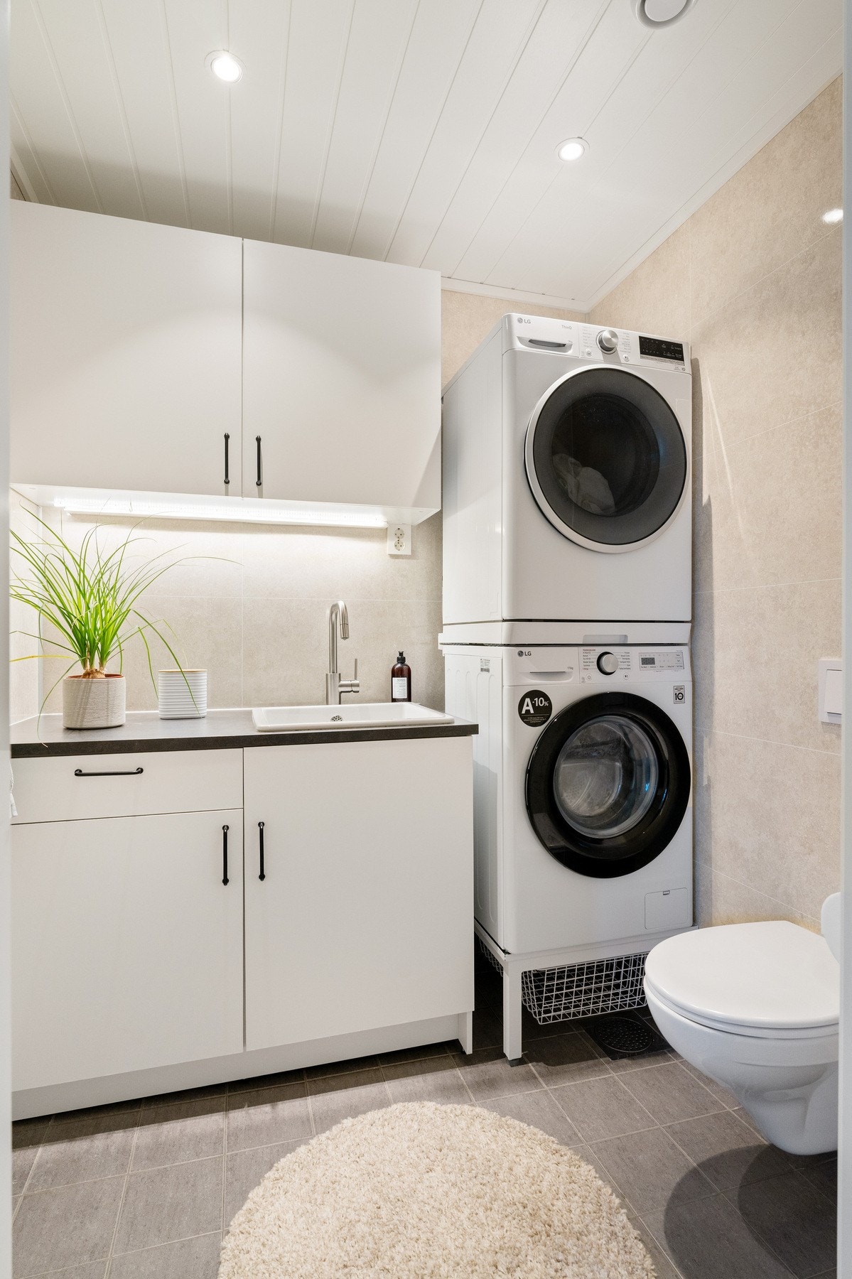 Praktisk vaskerom med klosett. Flis på gulv med varme og våtromsplater på vegg. Galleribilde