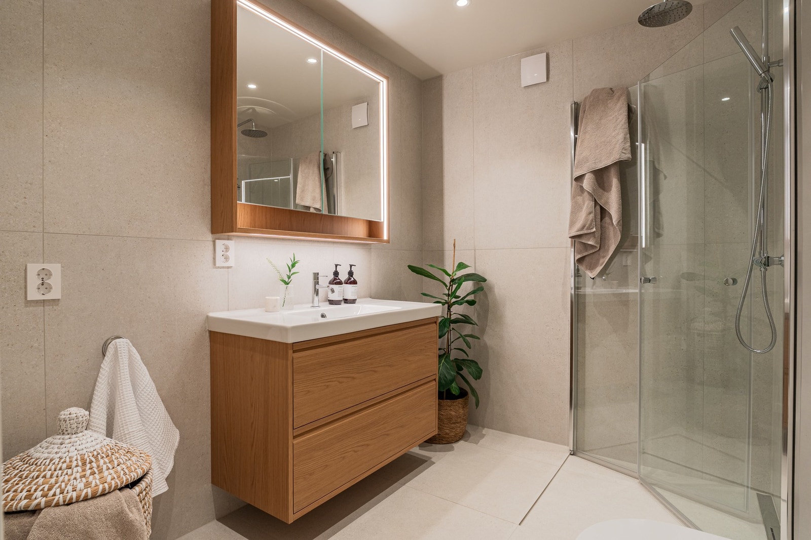 Dusjhjørnet har glassdører og både hånddusj og regndusj for økt komfort. Det er opplegg for vaskemaskin. Galleribilde