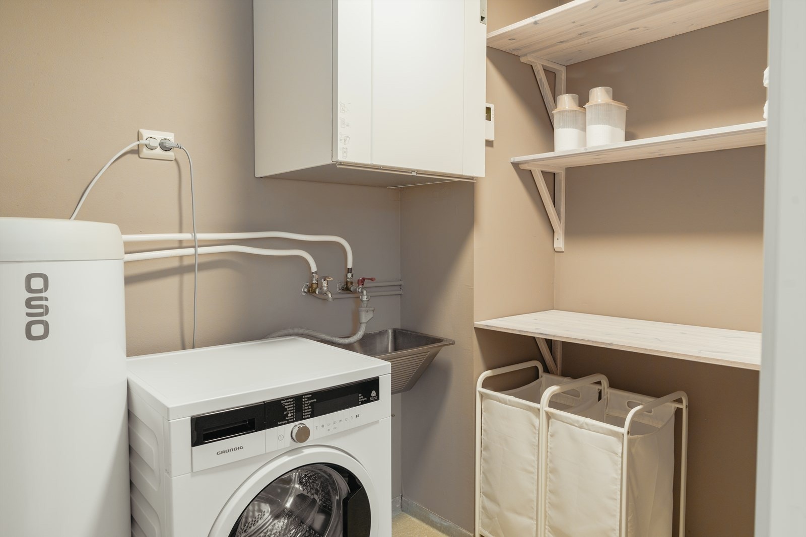 Eget vaskerom gir en praktisk hverdag. Overflatene ble malt i 2022, og det ble samtidig etablert ny himling i forbindelse med ventilasjon. Veggene har malte plater, taket er malt, og gulvet har vinylbelegg - et funksjonelt og vedlikeholdsvennlig rom. Galleribilde