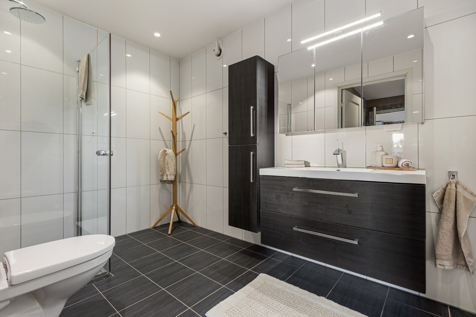 Badet er helfliset med mørke gulvfliser og lyse veggfliser. Galleribilde