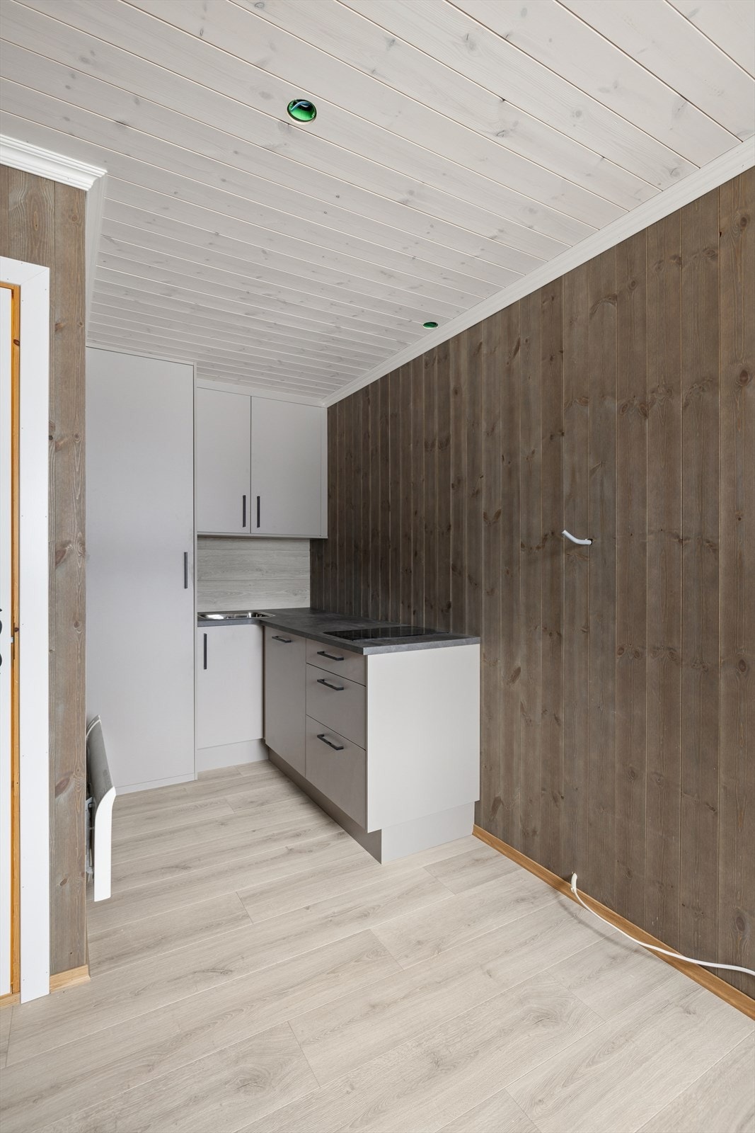 Kjøkkenet har en enkel og lys innredning med laminerte skrog og glatte fronter. Benkeplaten er i laminat og er utstyrt med kjøkkenkum. Galleribilde