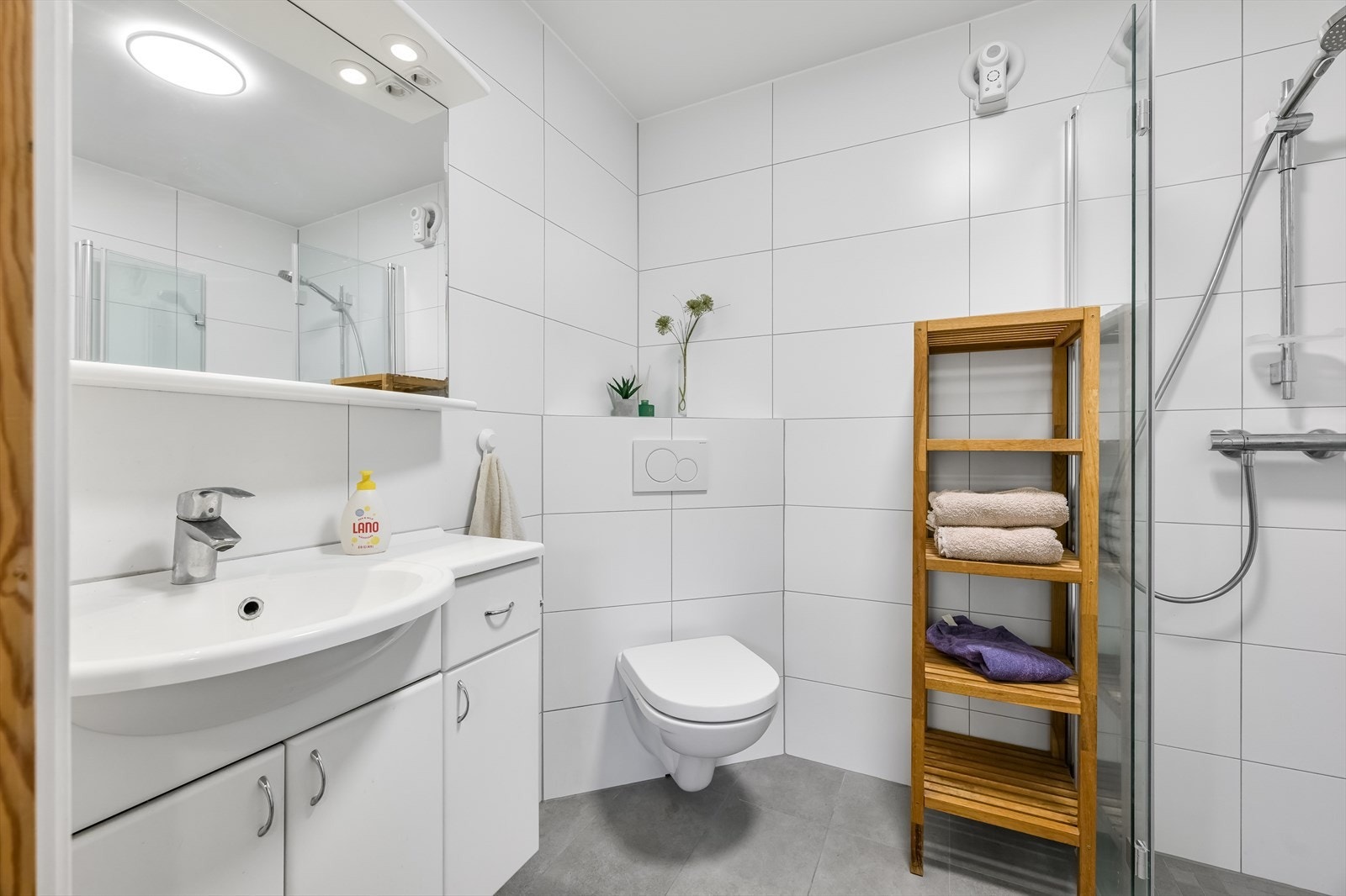 Badet er innredet med hvite veggfliser og lysegrå gulvfliser. Galleribilde