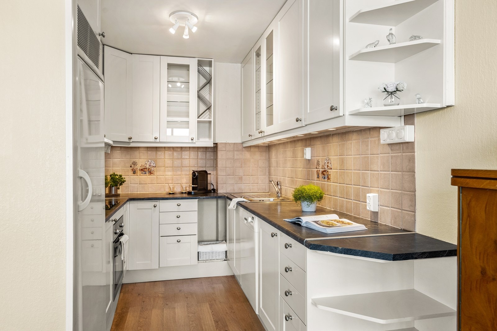 Kjøkkenet har hvit innredning med en enkel og tidløs profil Galleribilde