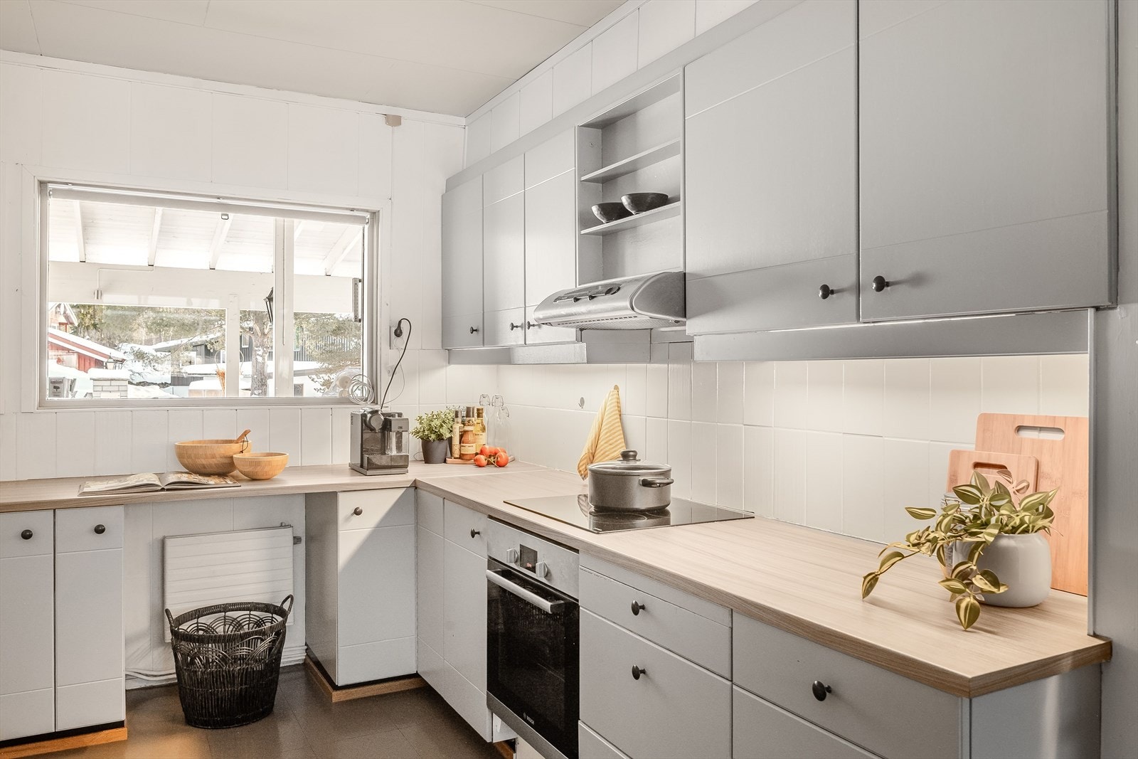 Innredningen har lysegrå fronter, laminert benkeplate, fliser i benkeryggen og belysning under overskapene. Galleribilde