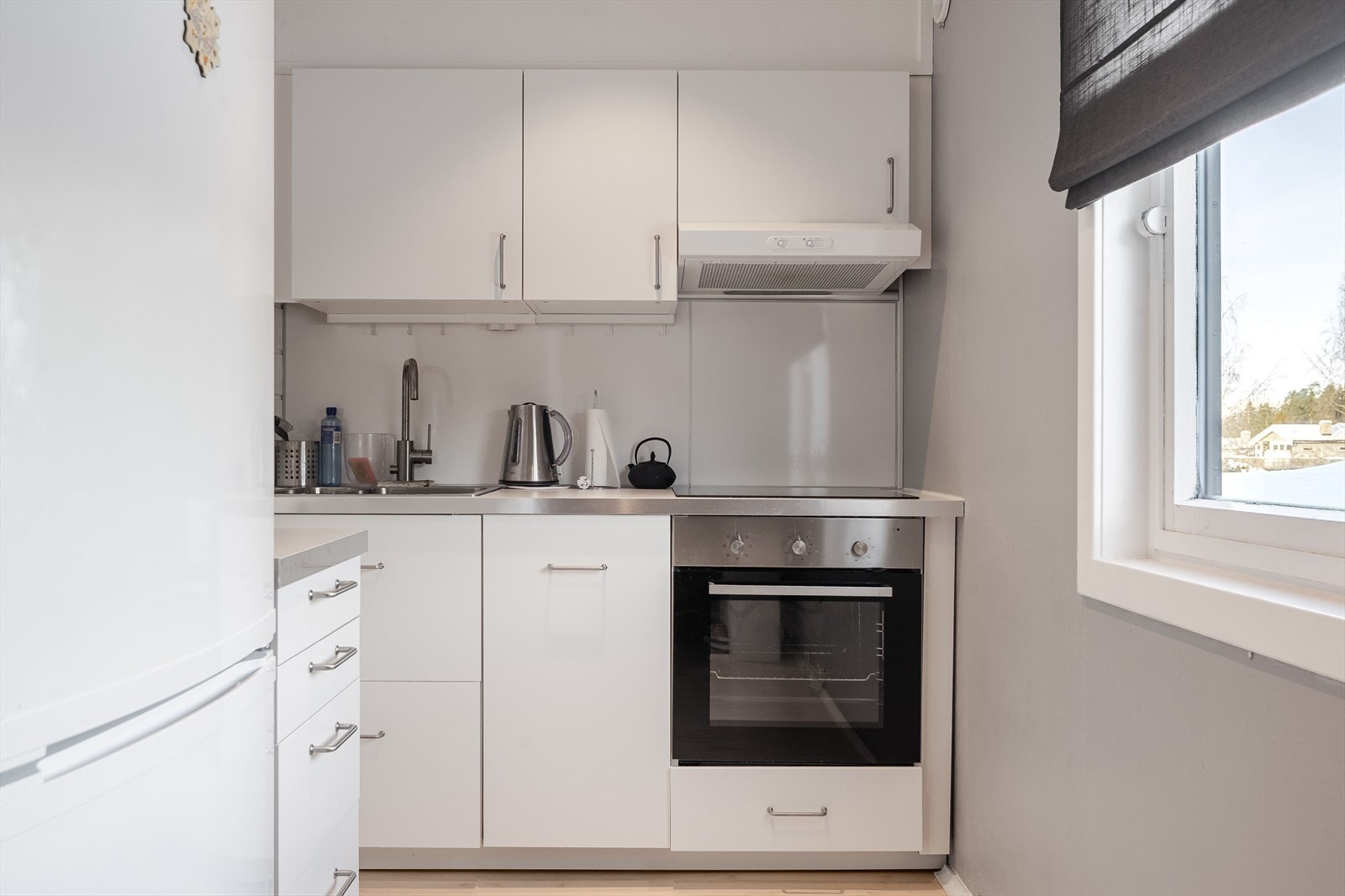 Lys kjøkkeninnredning fra Ikea som var ny i 2018. Innredningen har hvite glatte fronter og laminert benkeplate med nedfelt oppvaskkum. Integrert oppvaskmaskin, koketopp og stekeovn. Kjøkkenventilator med avtrekk ut. Galleribilde