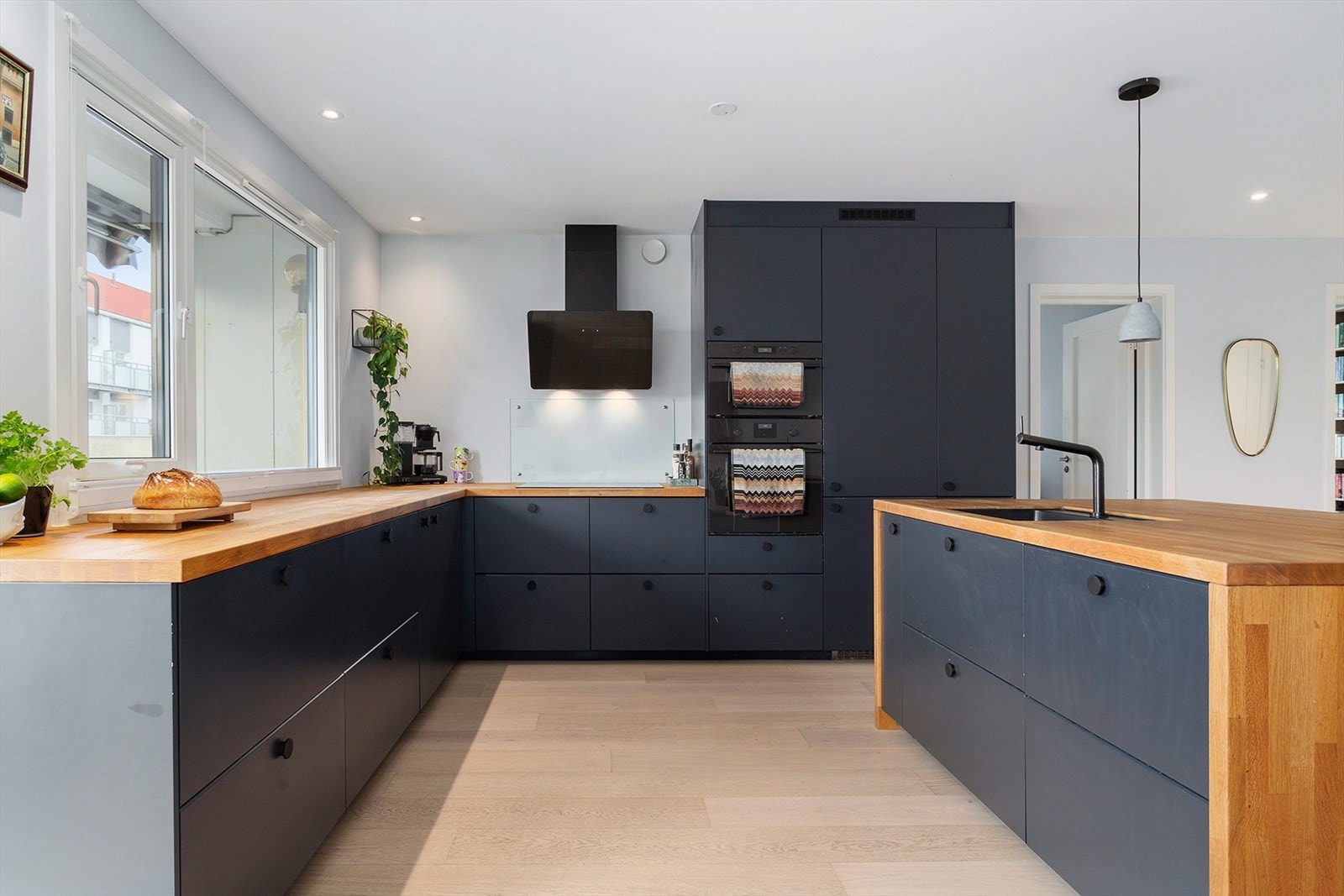 Moderne kjøkken med mørke fronter, heltre benkeplate og gjennomførte detaljer Galleribilde