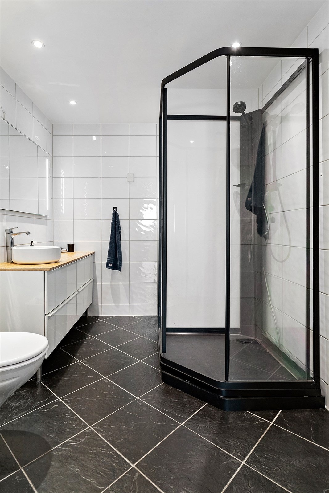 Flislagt bad med stilren innredning og integrerte downlights i taket. Galleribilde