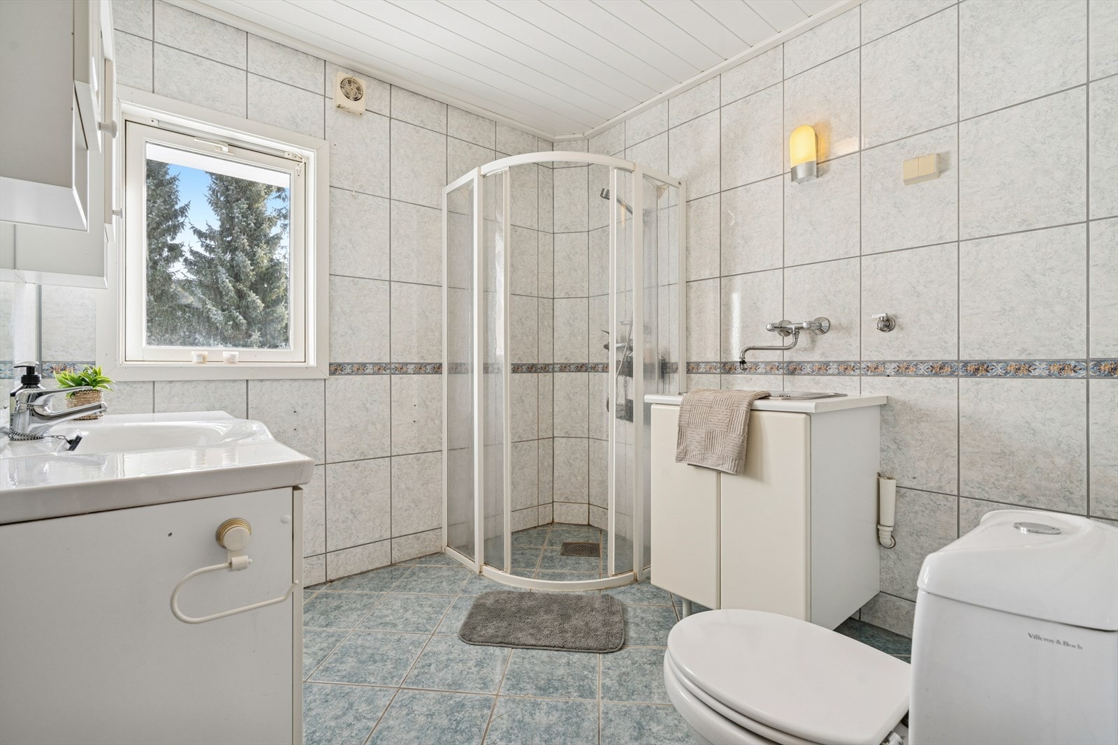 Helfliset bad - Rommet er innredet med servant, toalett og et dusjhjørne med dusjvegger. Ventilasjonen er mekanisk med en elektrisk styrt vifte. Galleribilde