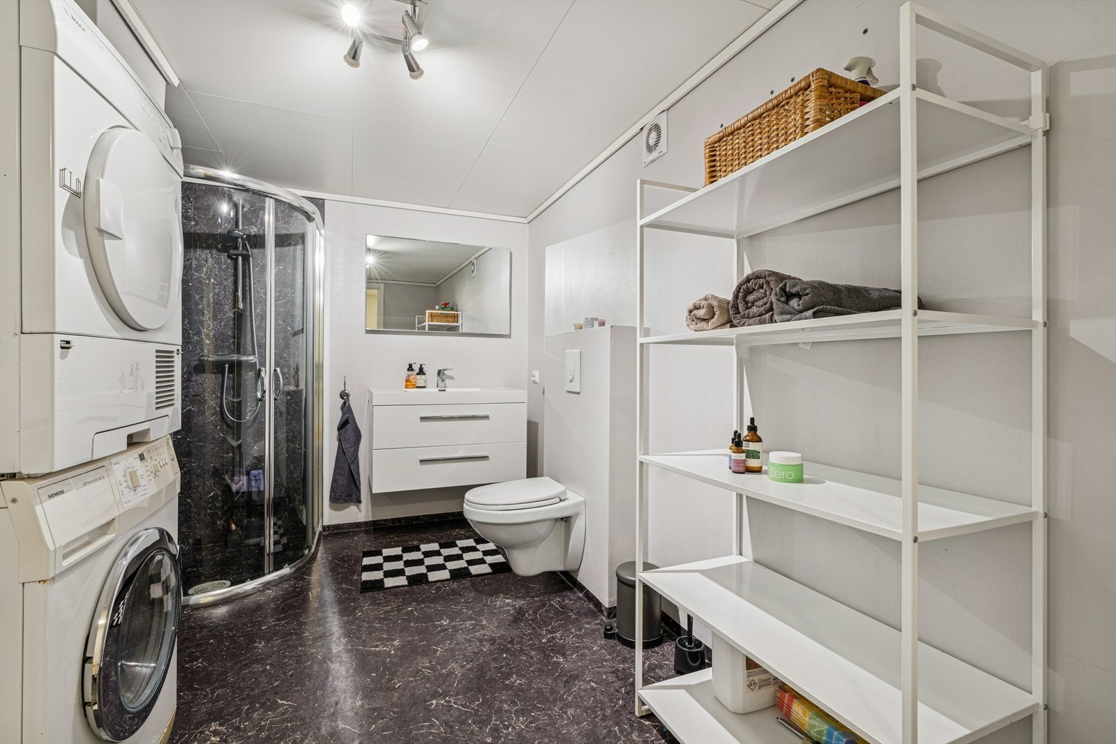 Rommet har innredning med nedfelt servant, veggmontert toalett, dusjvegger/hjørne og opplegg for vaskemaskin. Elektrisk styrt vifte. Galleribilde