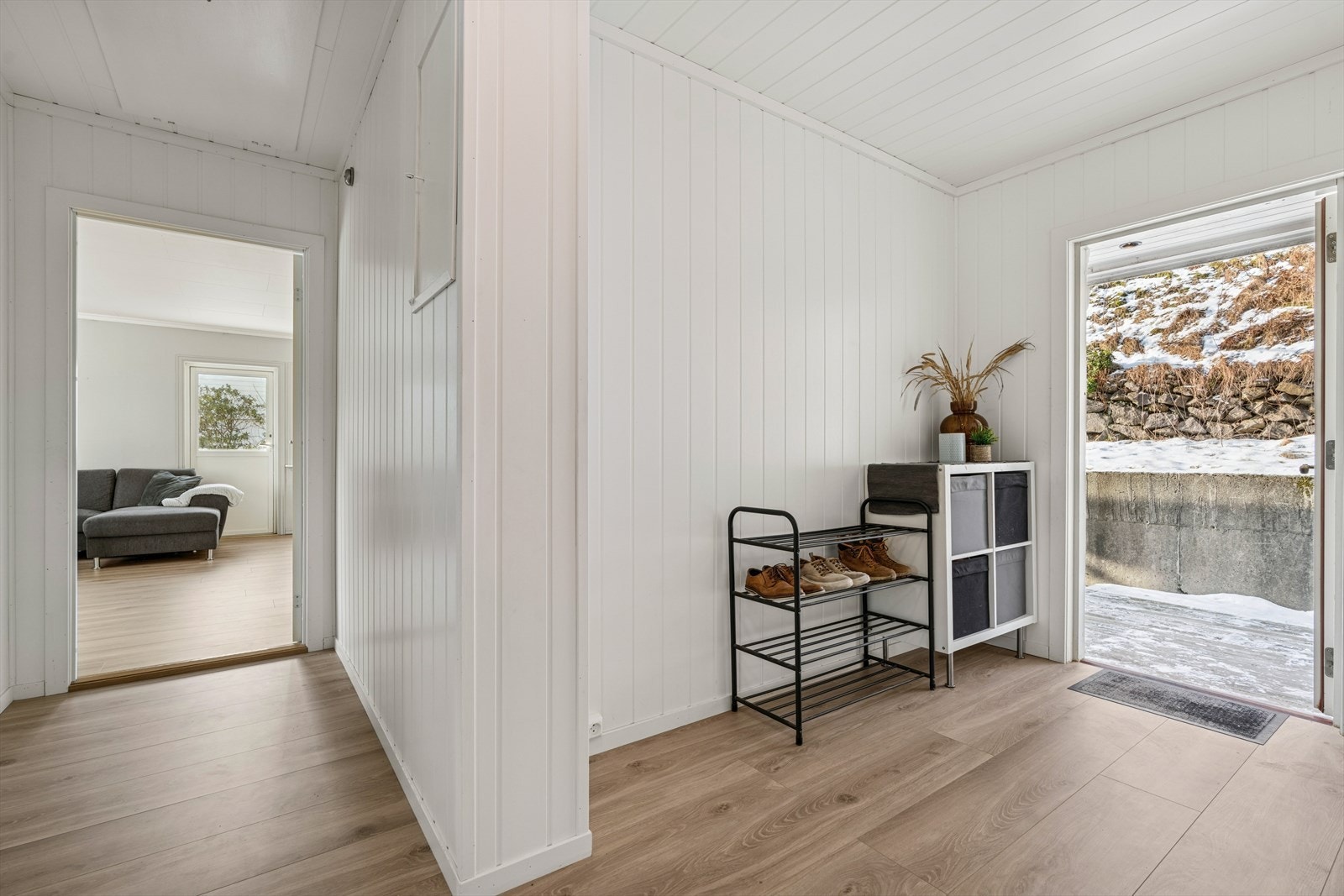 Fra et overbygget inngangsparti kommer du inn i en lys og innbydende entré som leder videre inn i boligens hovedetasje. Galleribilde