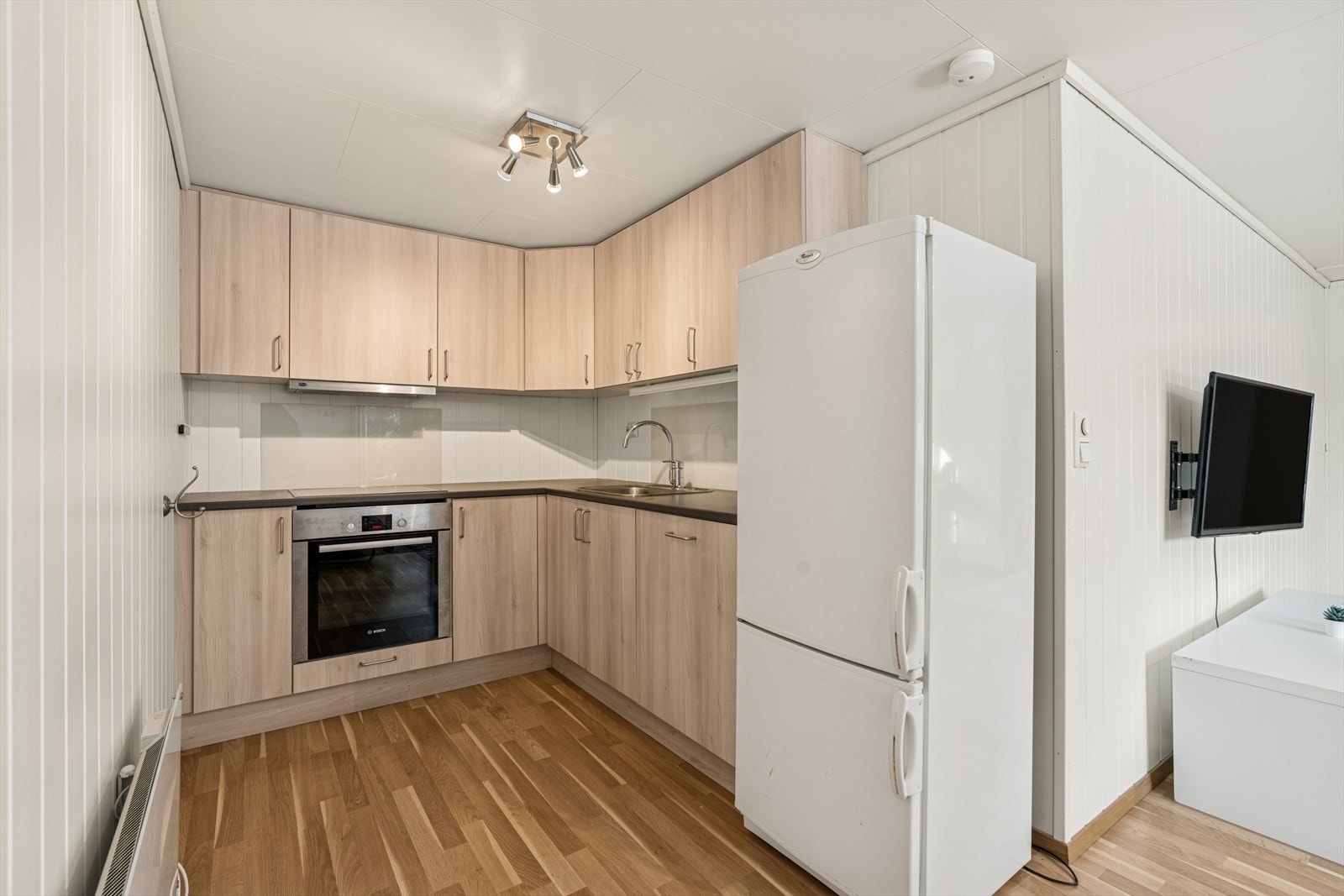 Åpen løsning mellom stue og kjøkken. Kjøkkeninnredningen har glatte fronter og laminatbenkeplate. Kjøkkenventilator med avtrekk ut. (Ikke søkt godkjent). Galleribilde