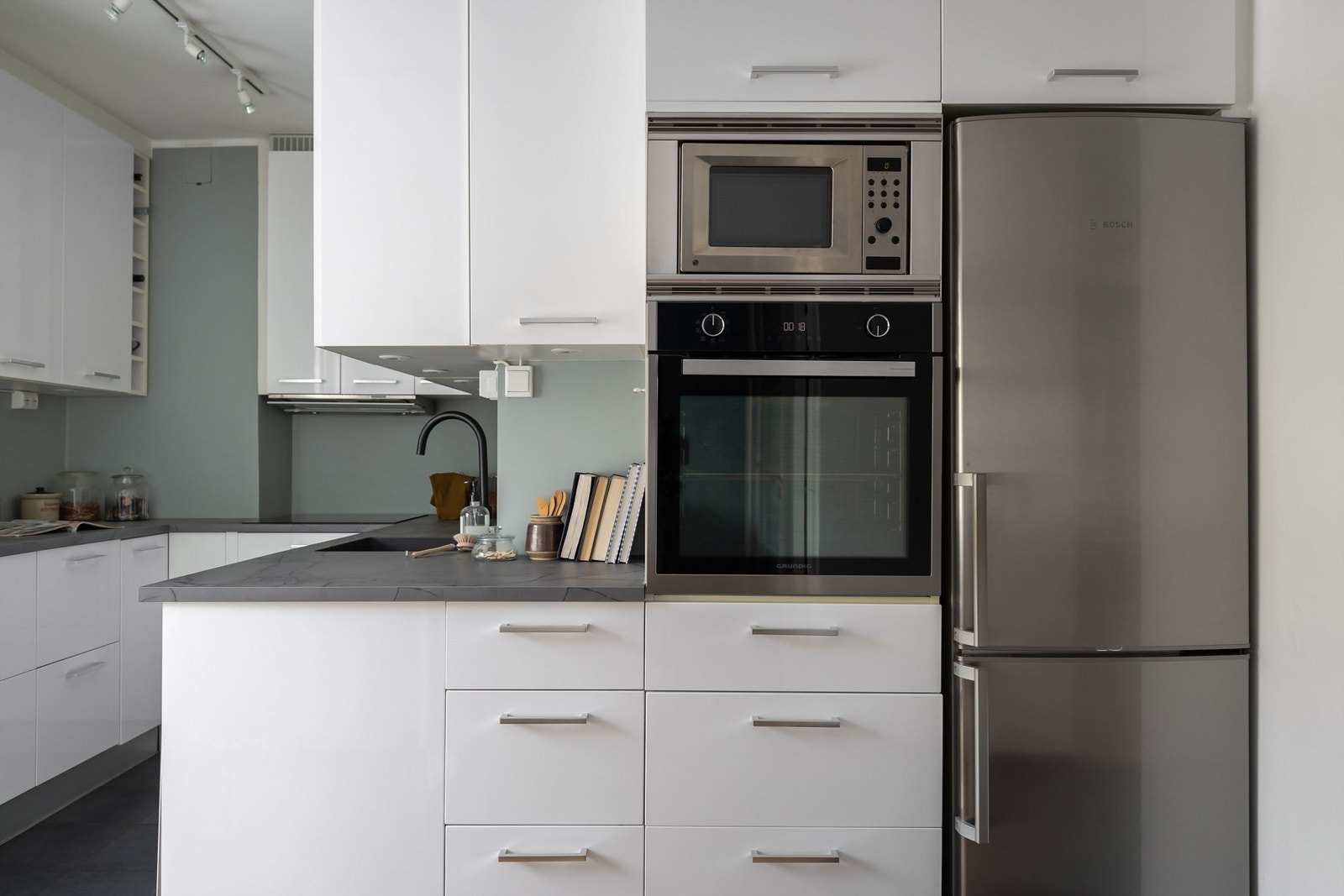 Integrerte hvitevarer som stekeovn, mikrobølgeovn og nedfelt koketopp med kullfilterventilator over Galleribilde