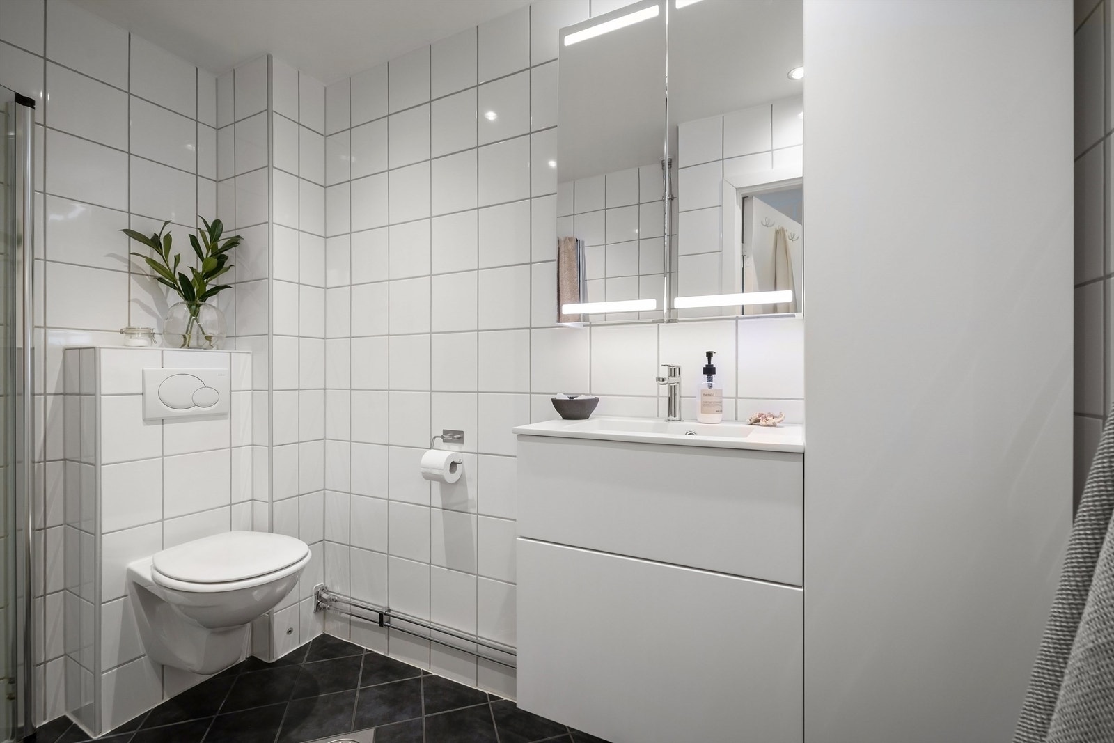 Et pent, flislagt bad med varmekabler, downlights i himling og opplegg for vaskemaskin Galleribilde