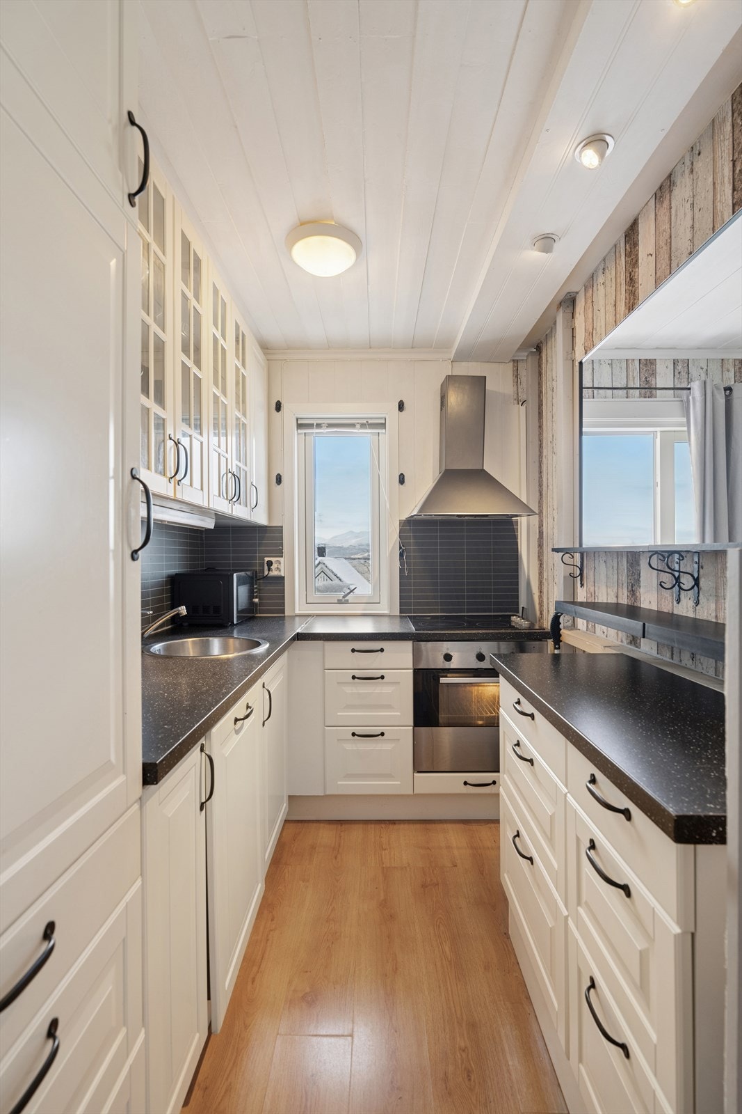 Kjøkkenet har profilerte fronter, vitrineskap og integrerte hvitevarer. Galleribilde