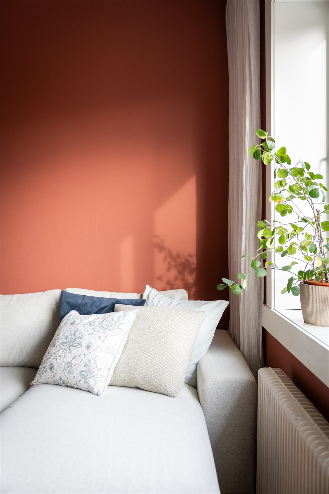 Veggen i stuen er malt i en varm terrakottatone som tilfører rommet karakter og dybde. Galleribilde