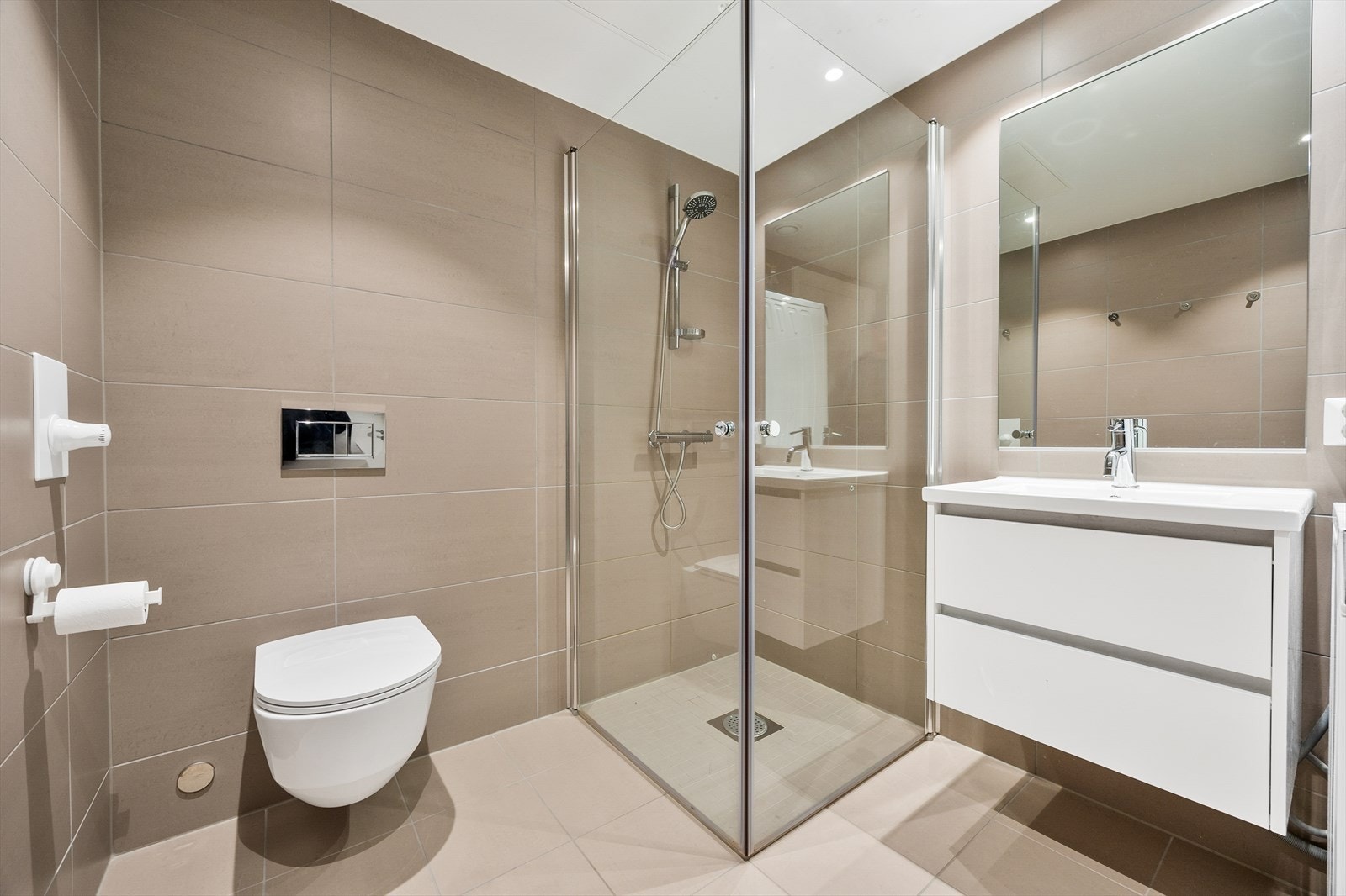 Badet er utstyrt med vegghengt toalett og dusjhjørne med dører i herdet glass. Galleribilde