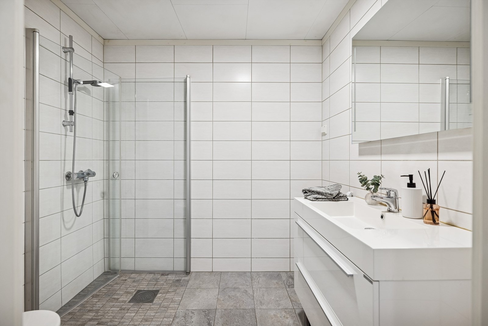 Bad med flislagt gulv, varmekabler og dusjhjørne. Funksjonell planløsning og opplegg for vaskemaskin. Galleribilde