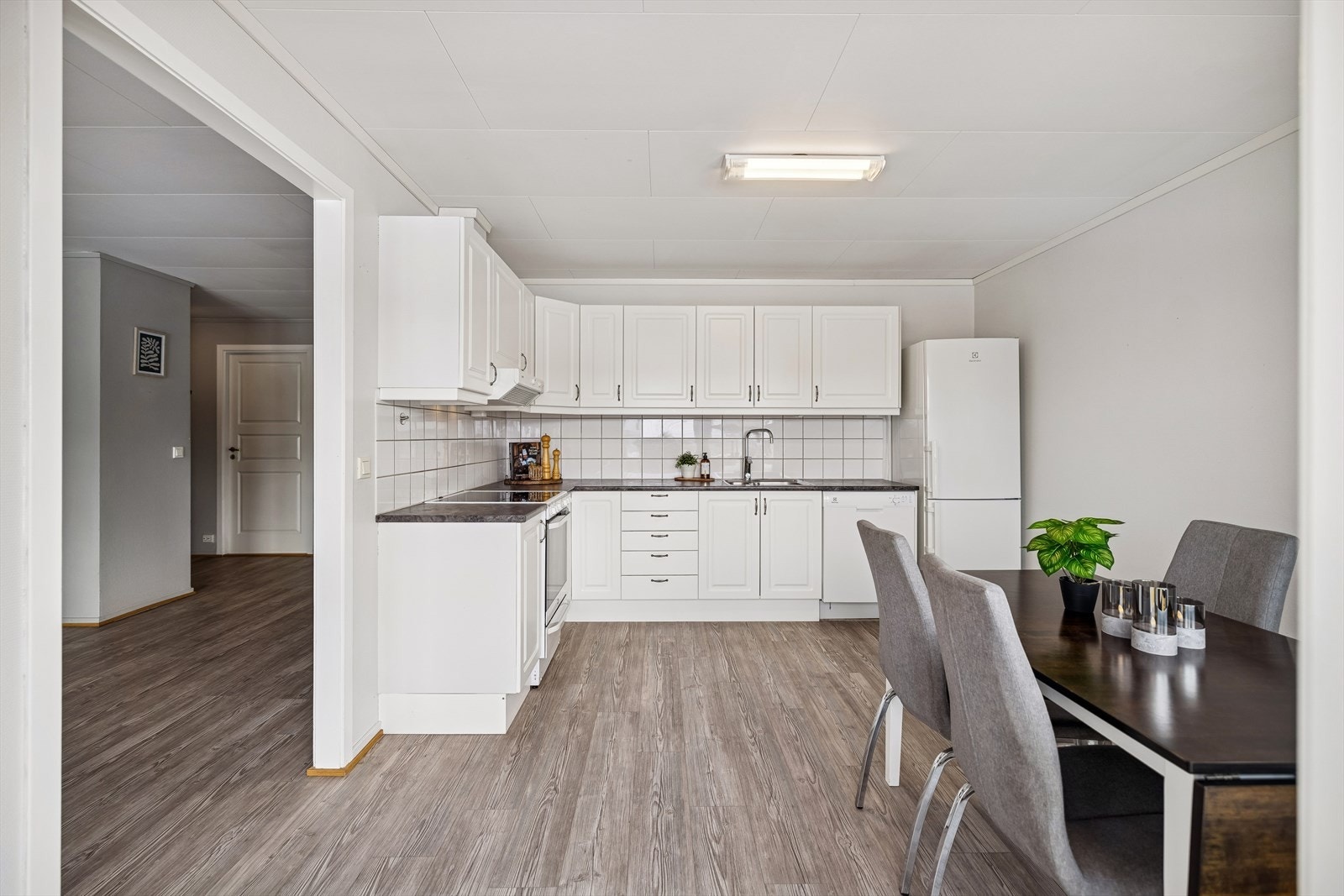 Lyst kjøkken med profilerte fronter, fliser mellom over- og underskap og god benkeplass. Galleribilde