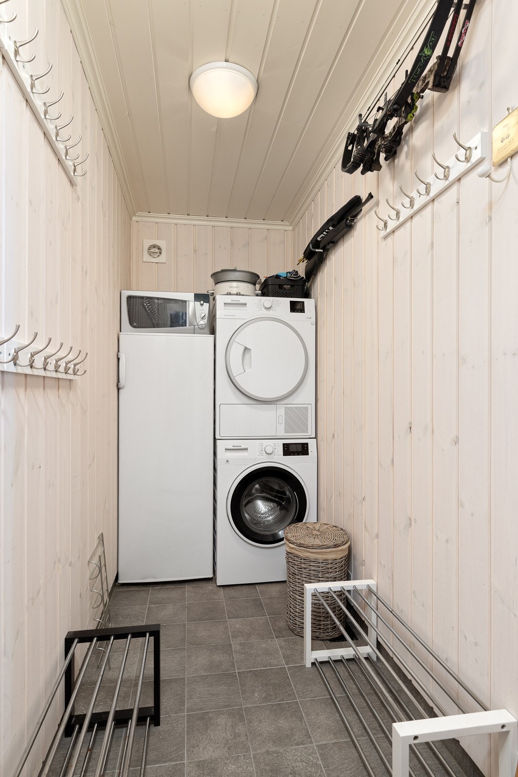 Rommet har opplegg for vaskemaskin og tørketrommel, samtidig som det gir plass til å henge opp yttertøy og oppbevare sko. Et funksjonelt rom for både oppbevaring og tørkeformål. Galleribilde