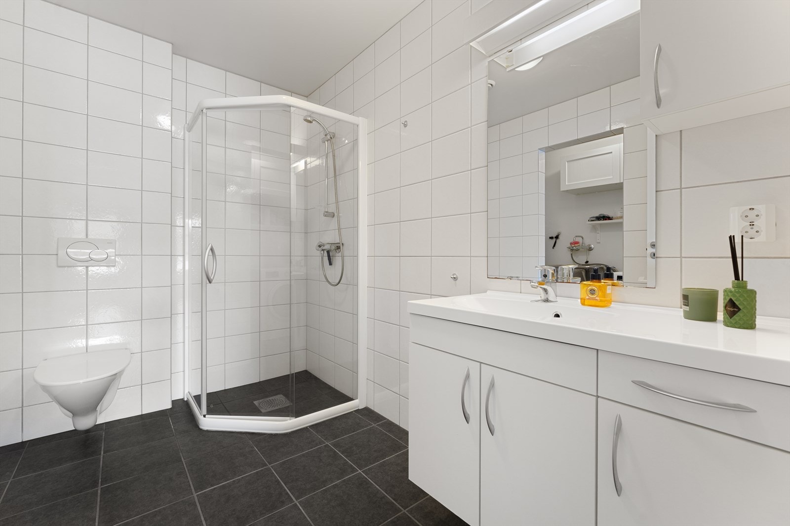 Baderommet er utstyrt med servantinnredning, dusjhjørne, vegghengt toalett, speil med overlys, rør-i-rør system og mekanisk avtrekk Galleribilde