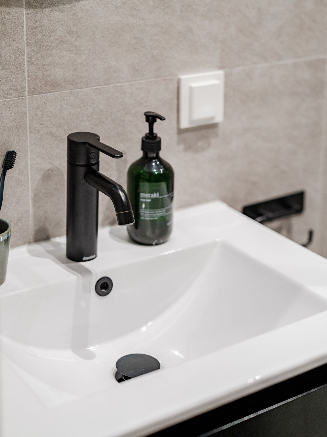 Vegghengt baderomsinnredning med heldekkende servant og servanskuffer i slett utførelse. Vegghengt rundt speil med lys. Galleribilde