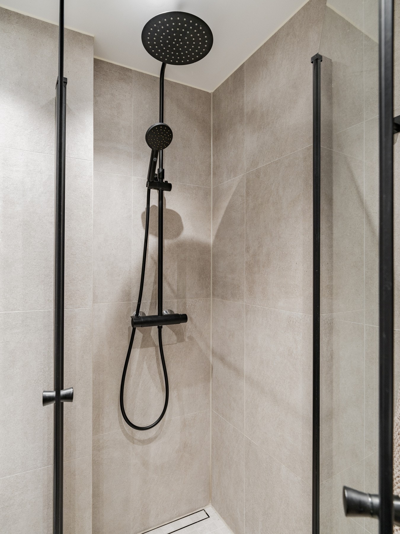 Nedsenket dusjsone med Purus rennesluk med klemring. Innfellbare dusjvegger i glass og vegghengt dusjgarnityr. Galleribilde