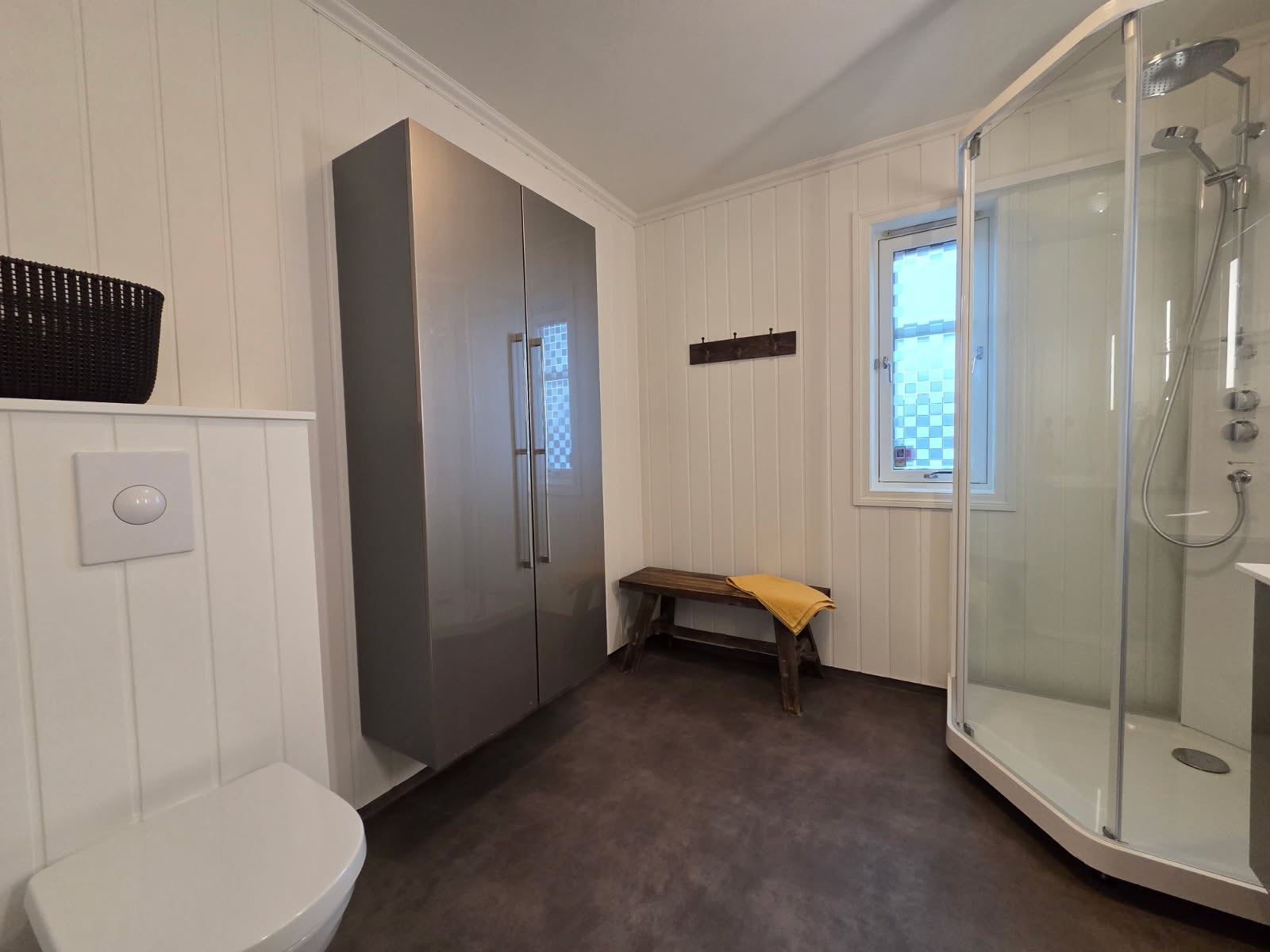 Badet er innredet med baderomsinnredning med servant, vegghengt toalett og dusjkabinett. Galleribilde