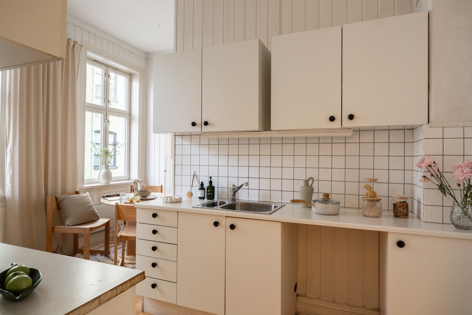 Lys kjøkkeninnredning med hvite glatte fronter og laminert benkeplate med nedfelt oppvaskkum. Galleribilde