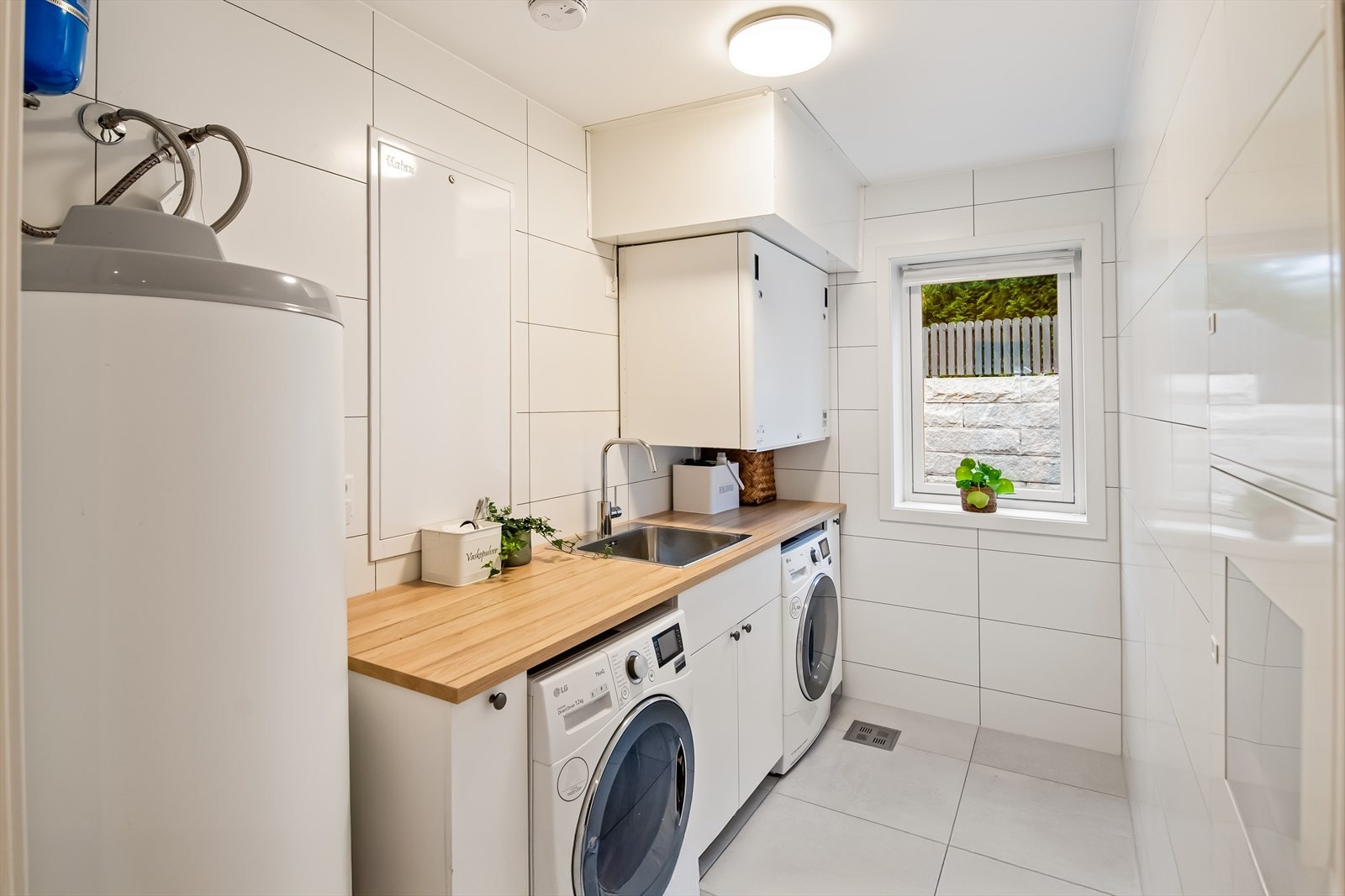 Separat og praktisk vaskerom innredet med benk, nedfelt skyllekum i skapinnredning og opplegg for vaskemaskin og tørketrommel. Her er også boligens ventilasjonsanlegg med varmegjenvinning og 300 liters varmtvannsbereder. Galleribilde