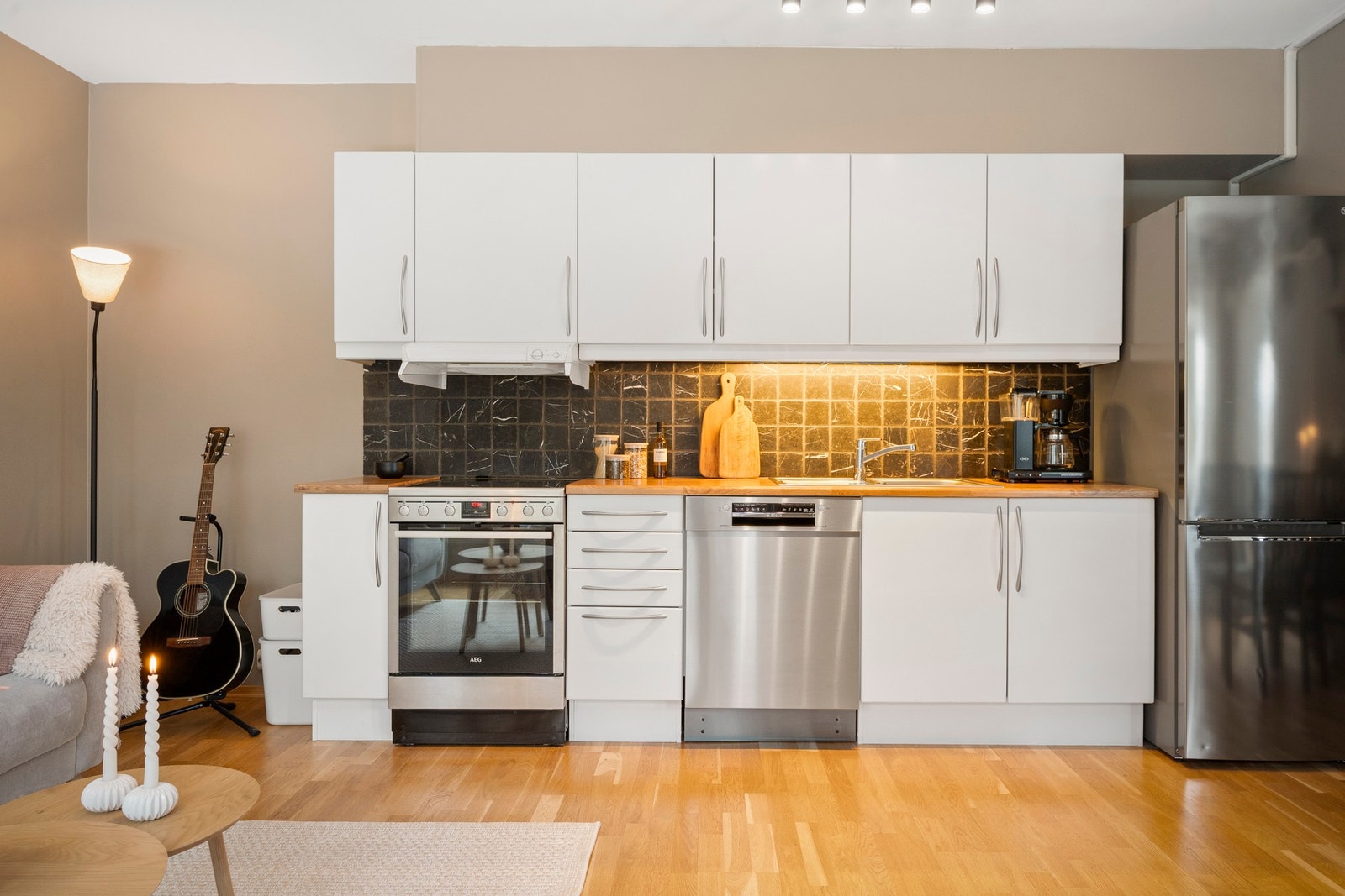 Kjøkkeninnredning med glatte hvite fronter og laminat benkeplate. Hvitevarer medfølger. Galleribilde