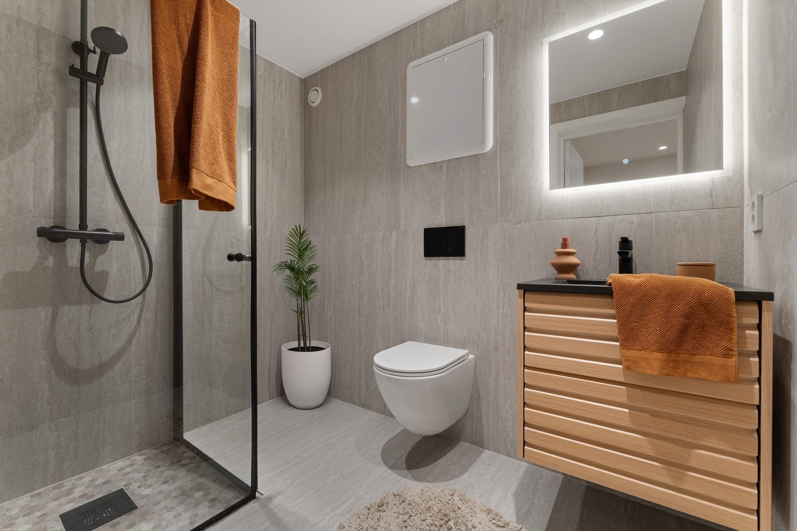 Delikat og moderne bad med elektriske varmekabler i gulv. Store fliser, vegghengt toalett og dusj med glassvegger gir et stilrent og tidløst uttrykk. Galleribilde