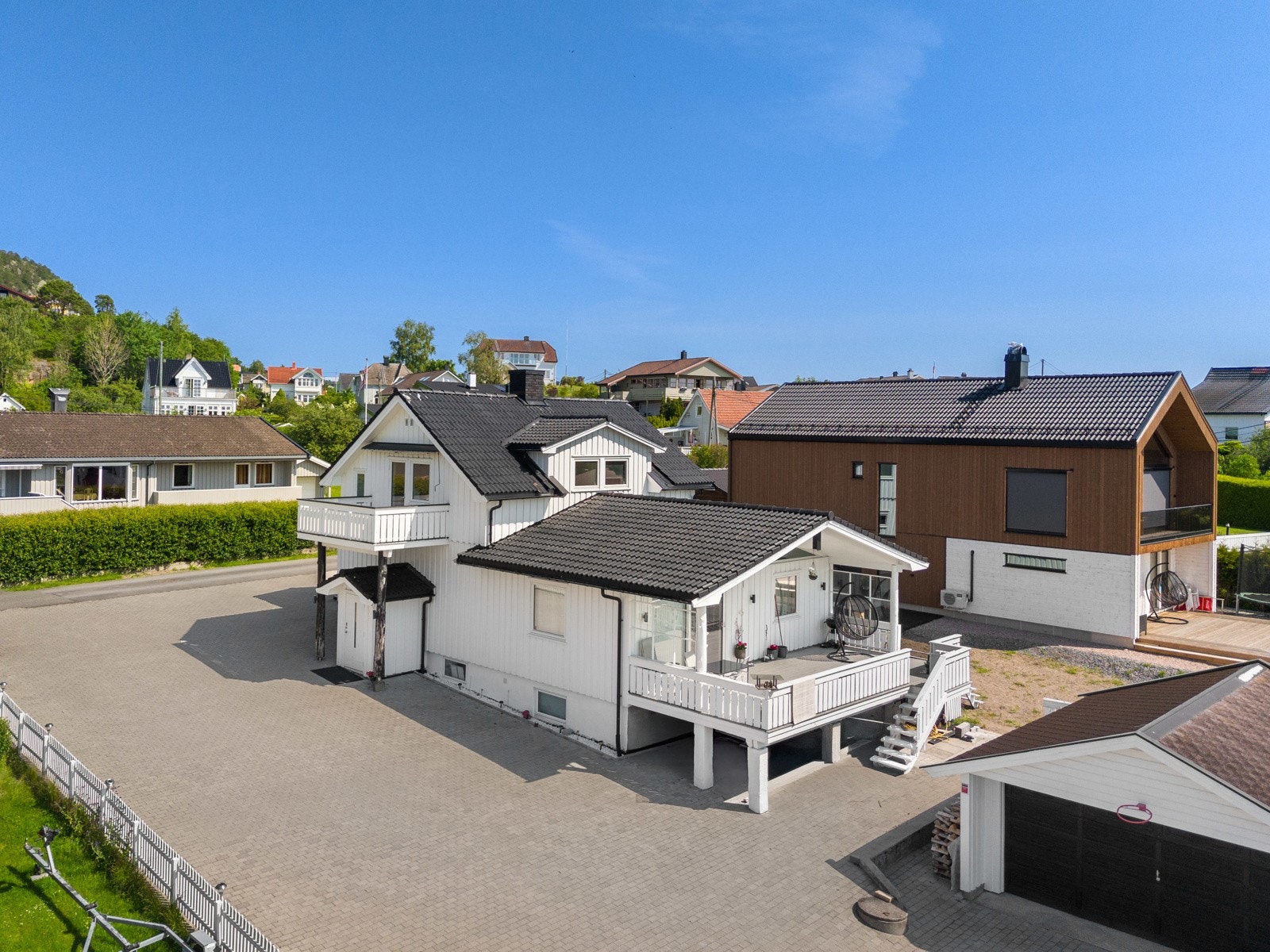 Romslig hellelagt gårdsplass med frittstående dobbelgarasje med elbillader Galleribilde