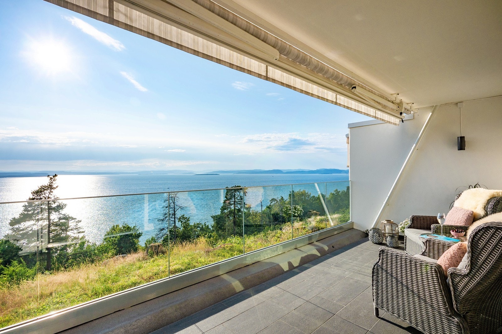 For solskjerming på varme dager er det montert en bred markise, gulvet er flislagt og stilig rekkverk i glass som gir full utnyttelse av utsikten. Fotograf: Marie Waagan Galleribilde