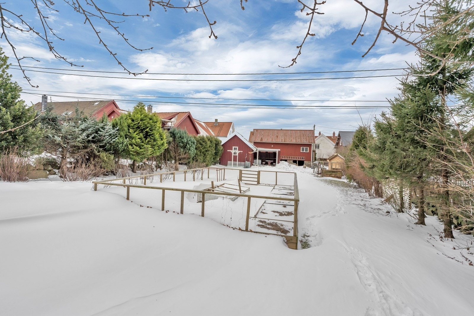 En kombinasjon av busker, blomster og trær som skaper en frodig ramme rundt eiendommen Galleribilde