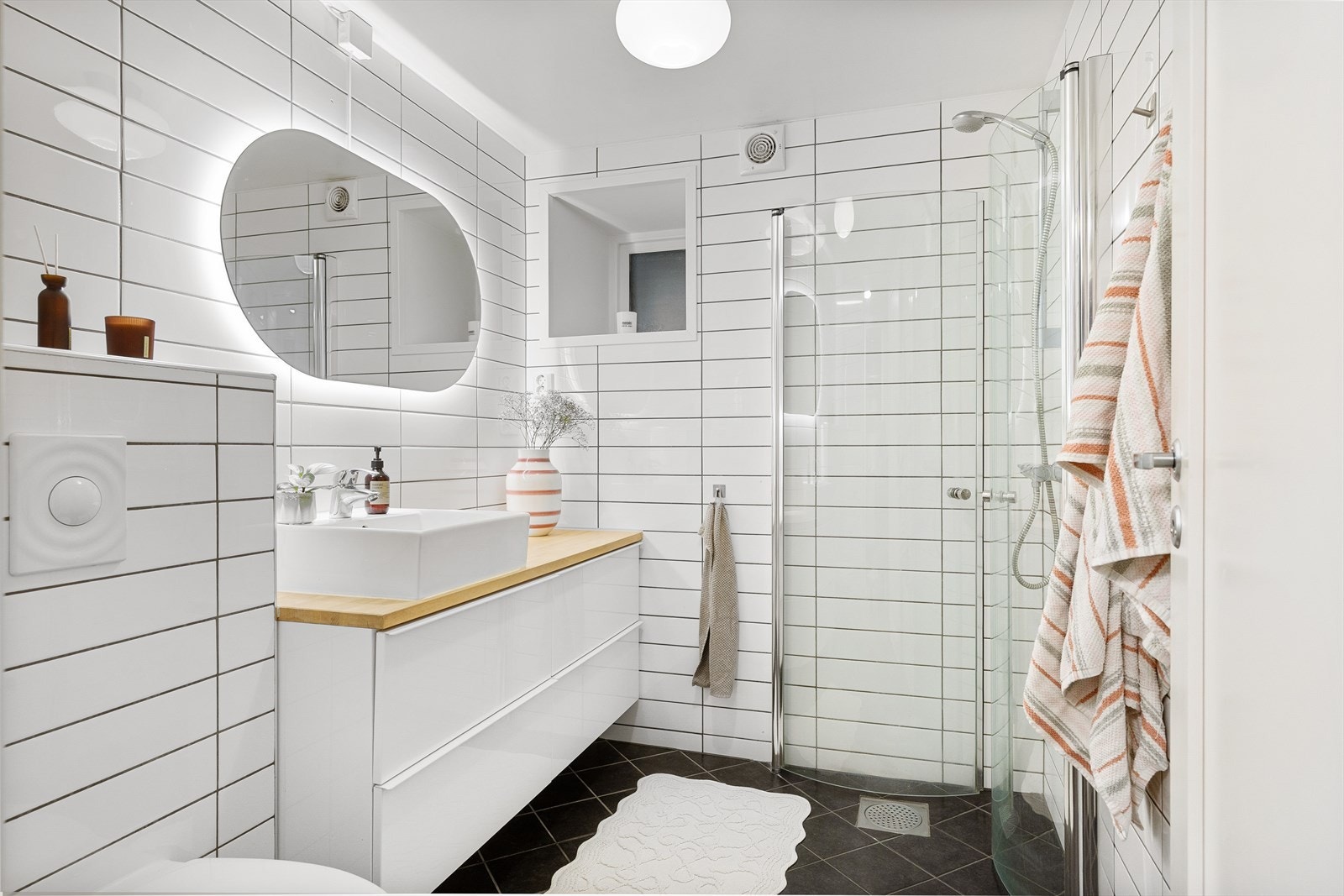 Tidløst bad fra 2011 med gulvvarme. Badet er utstyrt med mekanisk avtrekk, innfellbare dusjdører, vegghengt wc og servantskap med ettgreps blandebatteri fra Grohe. Galleribilde