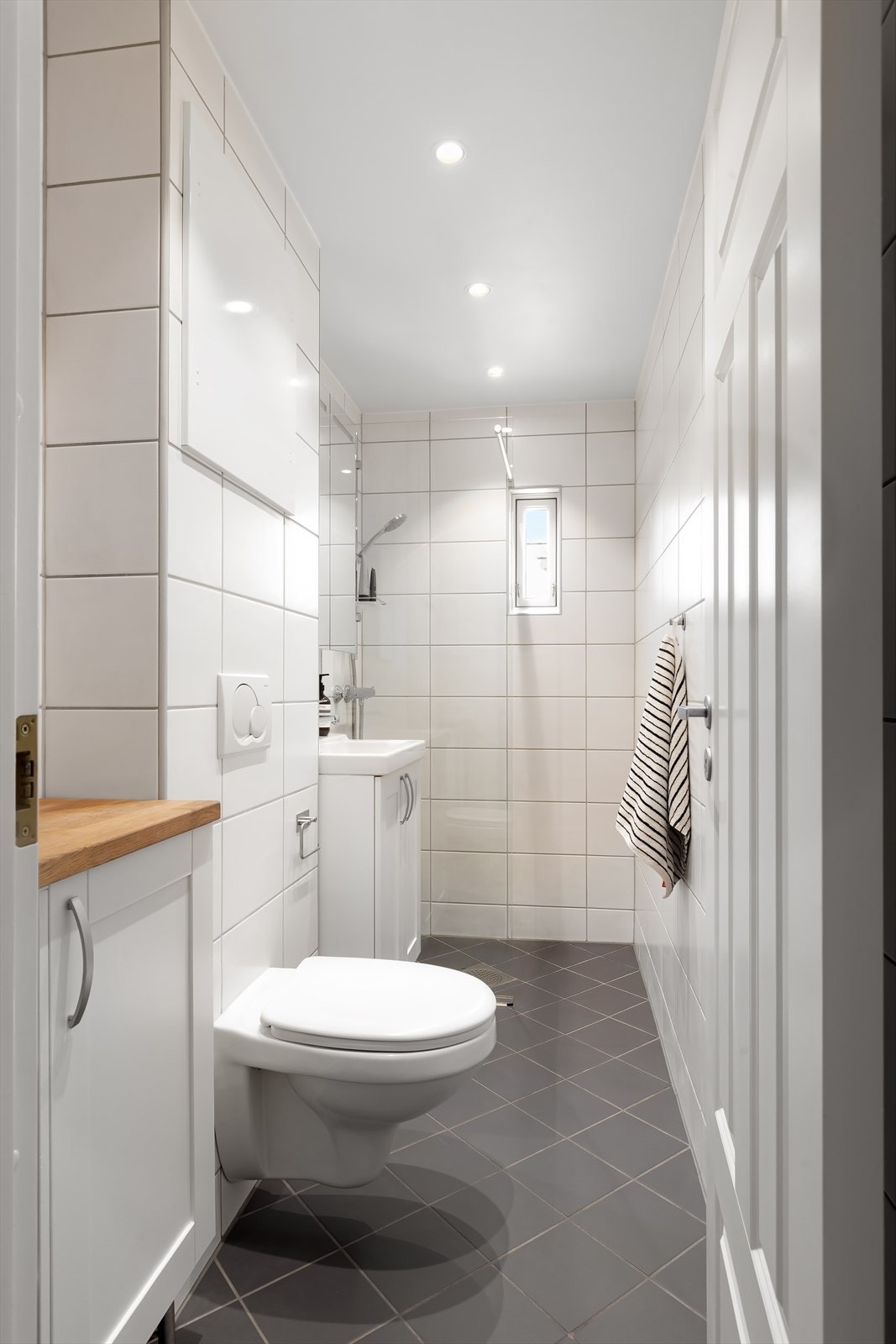 Pent, flislagt baderom med behagelige varmekabler i gulvet og diskret downlightsbelysning i taket. Galleribilde