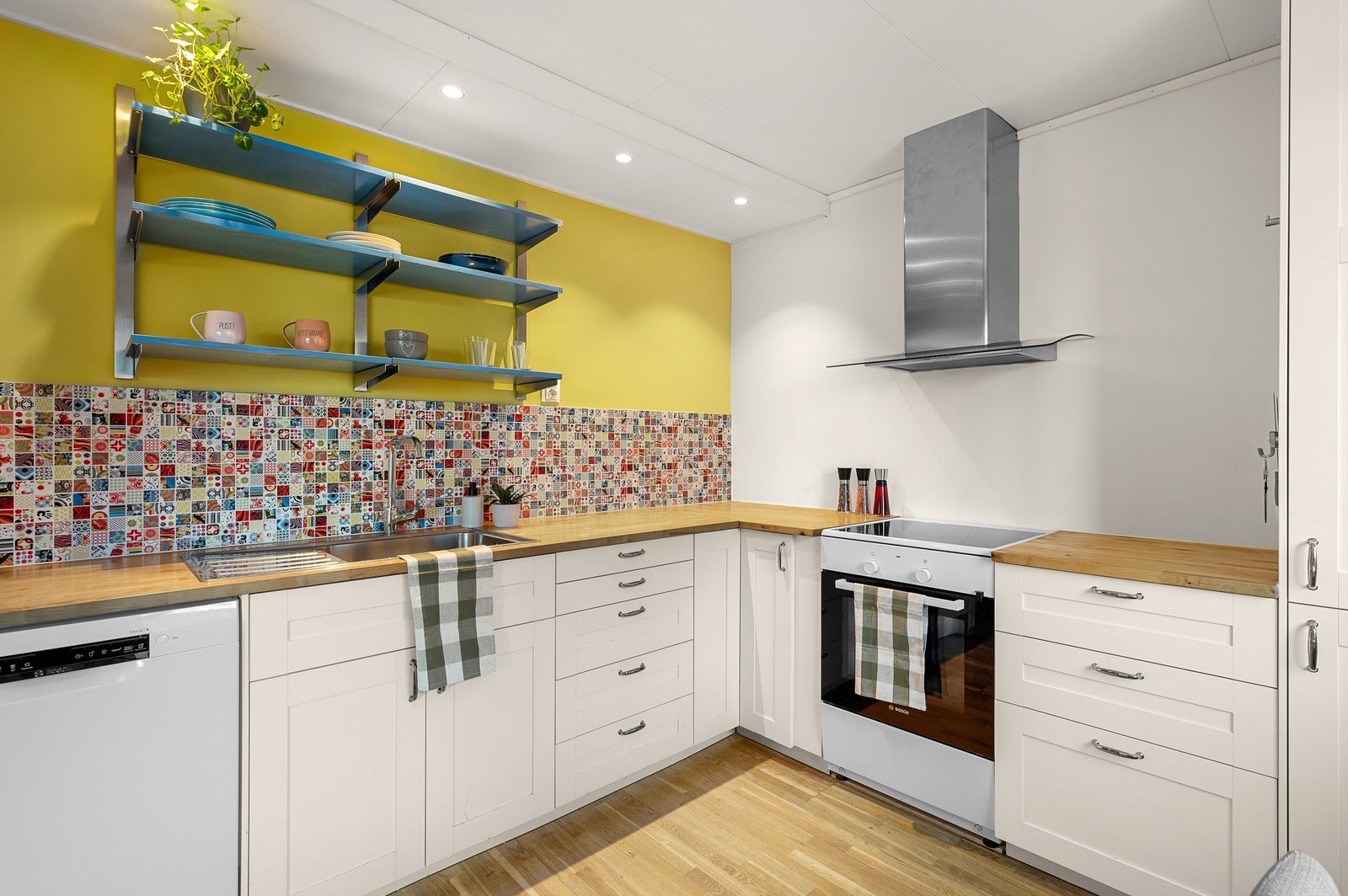 Kjøkkenet har rikelig med skap- og benkeplass samt fliser over benkeplaten. Galleribilde