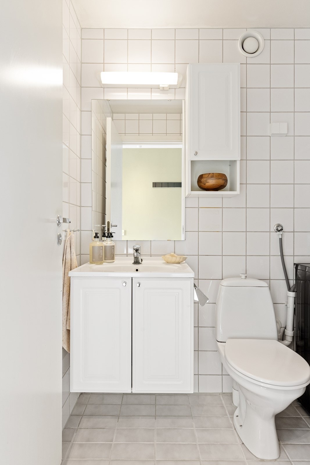 Badet er innredet med dusjhjørne, wc og servant. Fliser på gulv og vegger, mens himlingen har malt overflate. Mekanisk avtrekk bidrar til godt inneklima og det er opplegg for vaskemaskin. Galleribilde