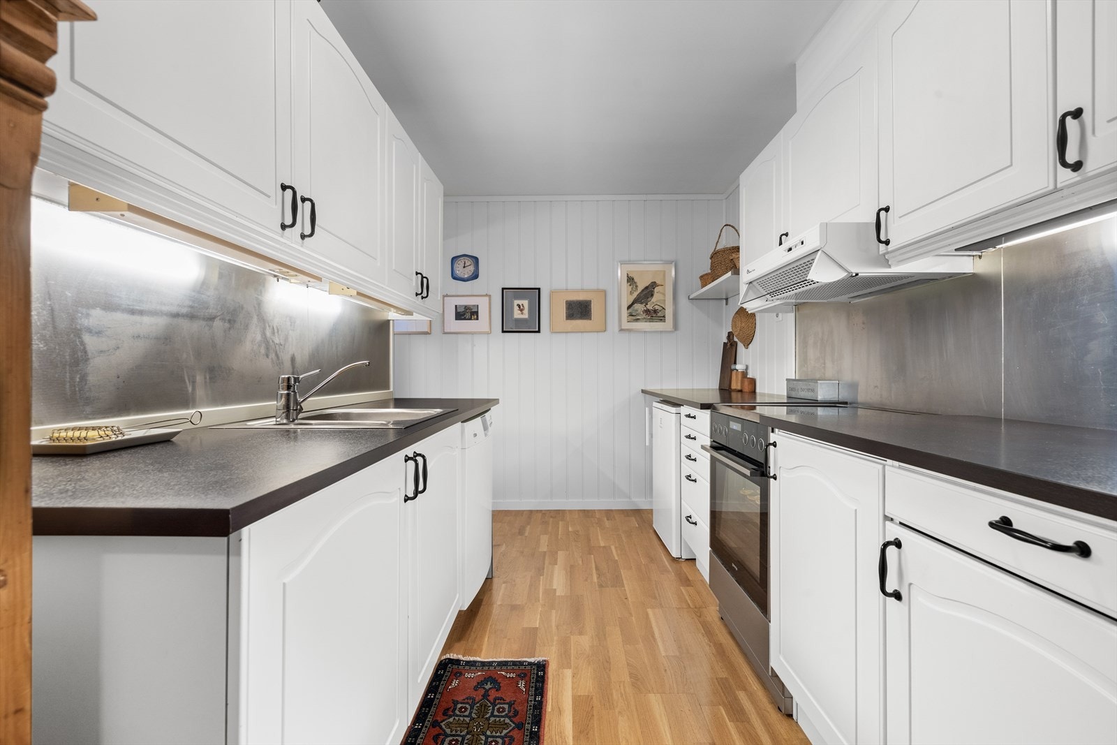 Kjøkkenet har profilert innredning med laminat benkeplate og stålplater mellom benk og overskap. Galleribilde