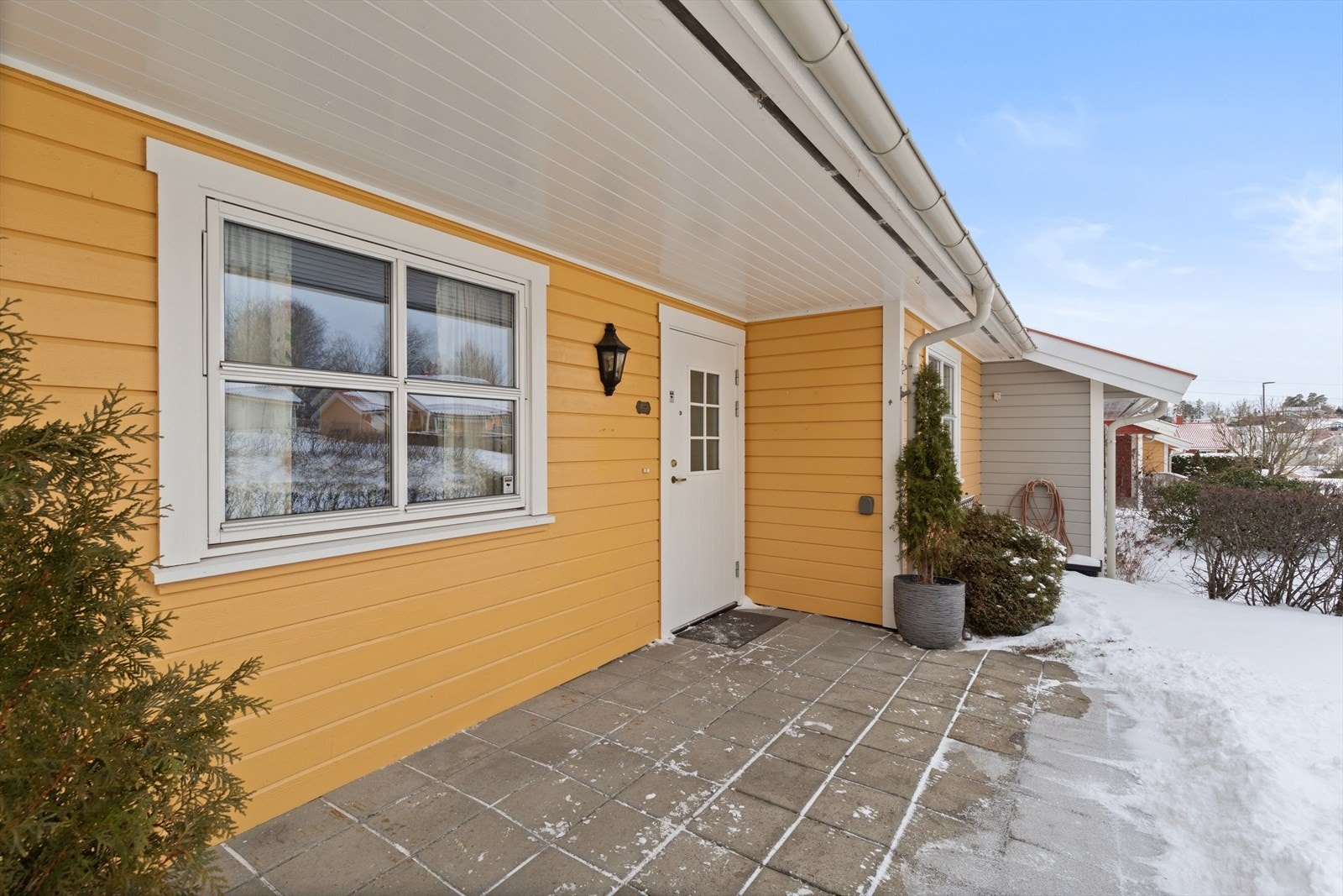 På nordsiden, i tilknytning til inngangspartiet, er det også naturlig sone for uteplass hvor dekket er hellelagt. Uteplassen er noe utvidet etter 2016 og ligger i sammenheng med en koselig liten hageflekk. Galleribilde