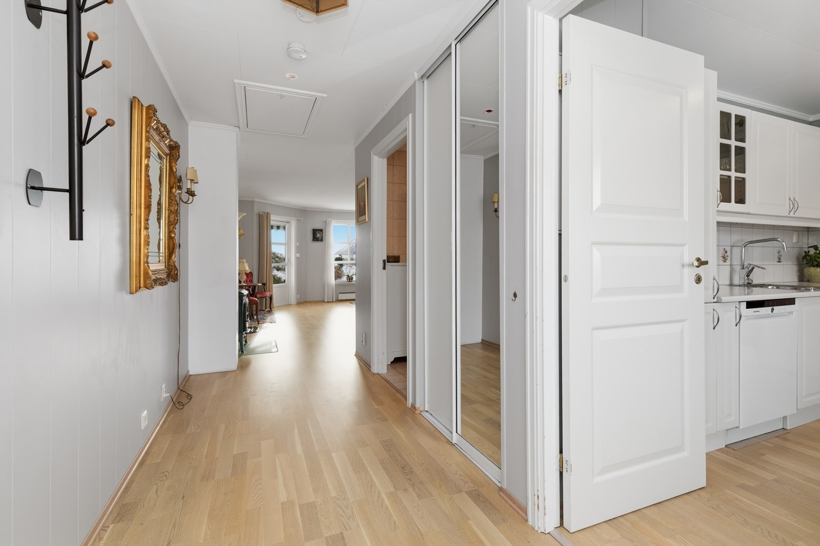 Vel innenfor boligens hovedinngangsdør, møter man en lys, innbydende og hyggelig entre og gang. Ytterklær og sko kan ryddes pent vekk i to dørs plassbygget skyvedørsgarderobe med speildører. Galleribilde
