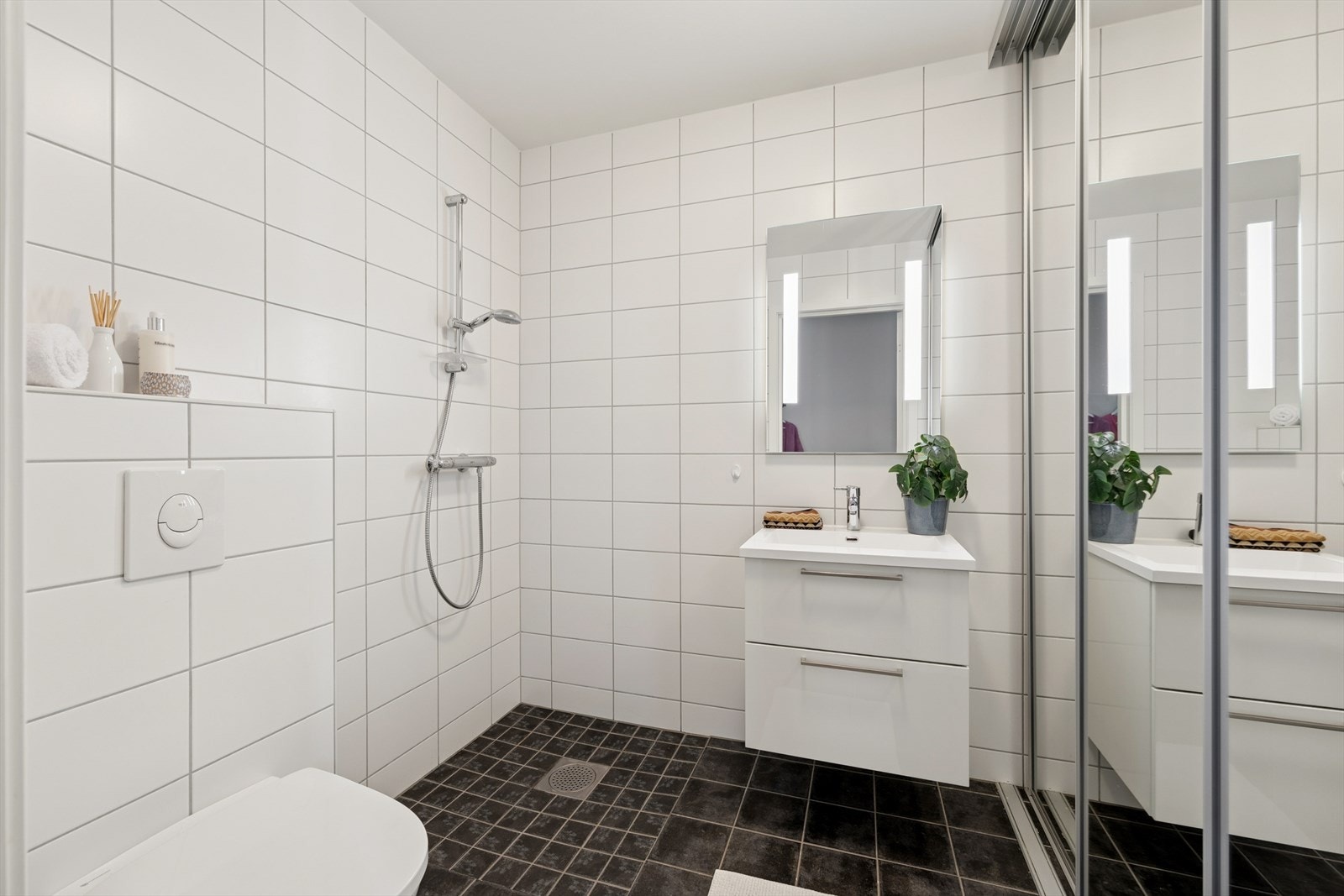 Boligen har et fullverdig baderom i hver etasje. Baderommet som er beliggende i første etasje har flislagte overflater på vegger og gulv. Opplegg for vaskemaskin og varmtvannstank er skjult bak skyvedørsgarderoben. Galleribilde