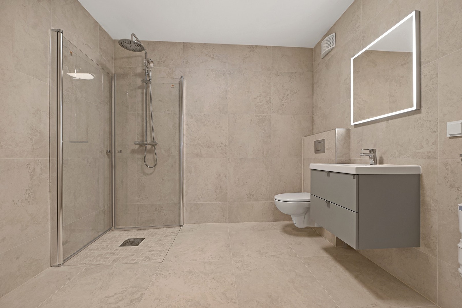 Leiligheten har et delikat bad. Innredningen er holdt i lyse og tidsriktige løsninger, gulvet er belagt med fliser og gulvvarme som gir behagelig, barfotvennlig varme. Galleribilde