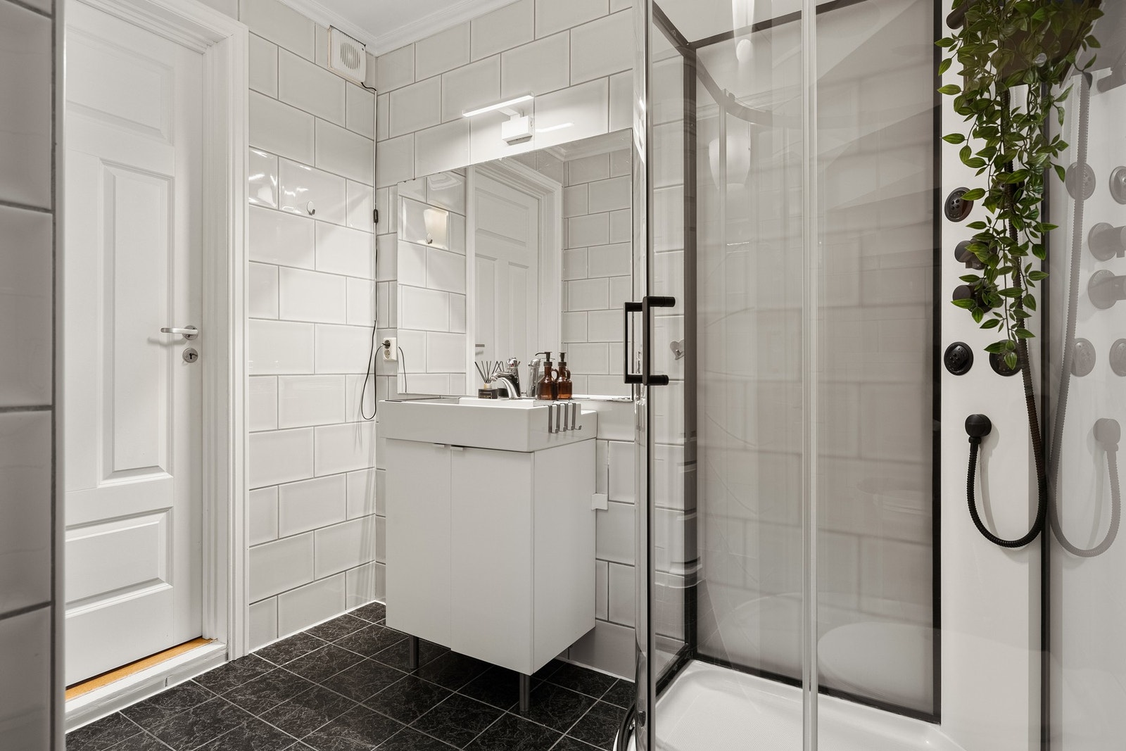 Badet er innredet med vegghengt toalett, servant med innredning og dusjkabinett. Galleribilde