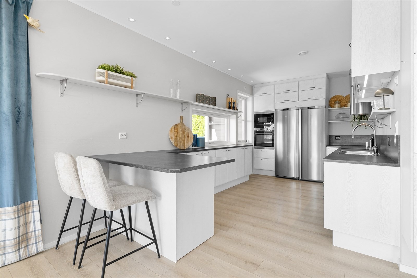 Delikat kjøkkeninnredning med slette, hvite fronter og benkeplate av laminat, som bærer et harmonisk samspill mellom eleganse og funksjonalitet. Galleribilde