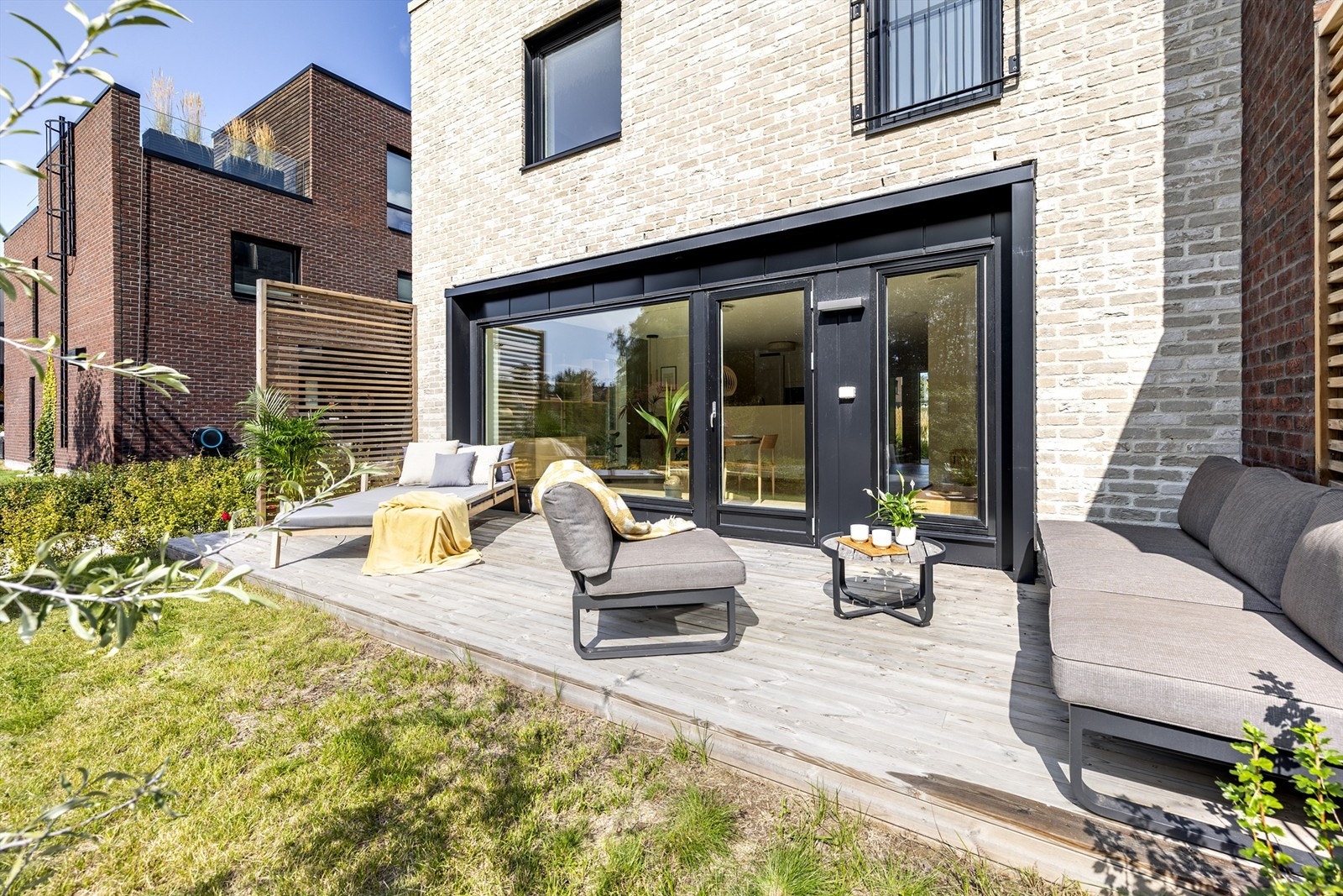 Theodor Hansens vei 7A - Boligen disponerer ca 180 kvm pent opparbeidet tomt rundt tre sider av boligen. Solrik markterrasse på ca 18 kvm samt hage i forlengelsen og plen langs bygget og på fremsiden. Foto: Martin Johnson (Sommerbilder) og Oh Shots Galleribilde