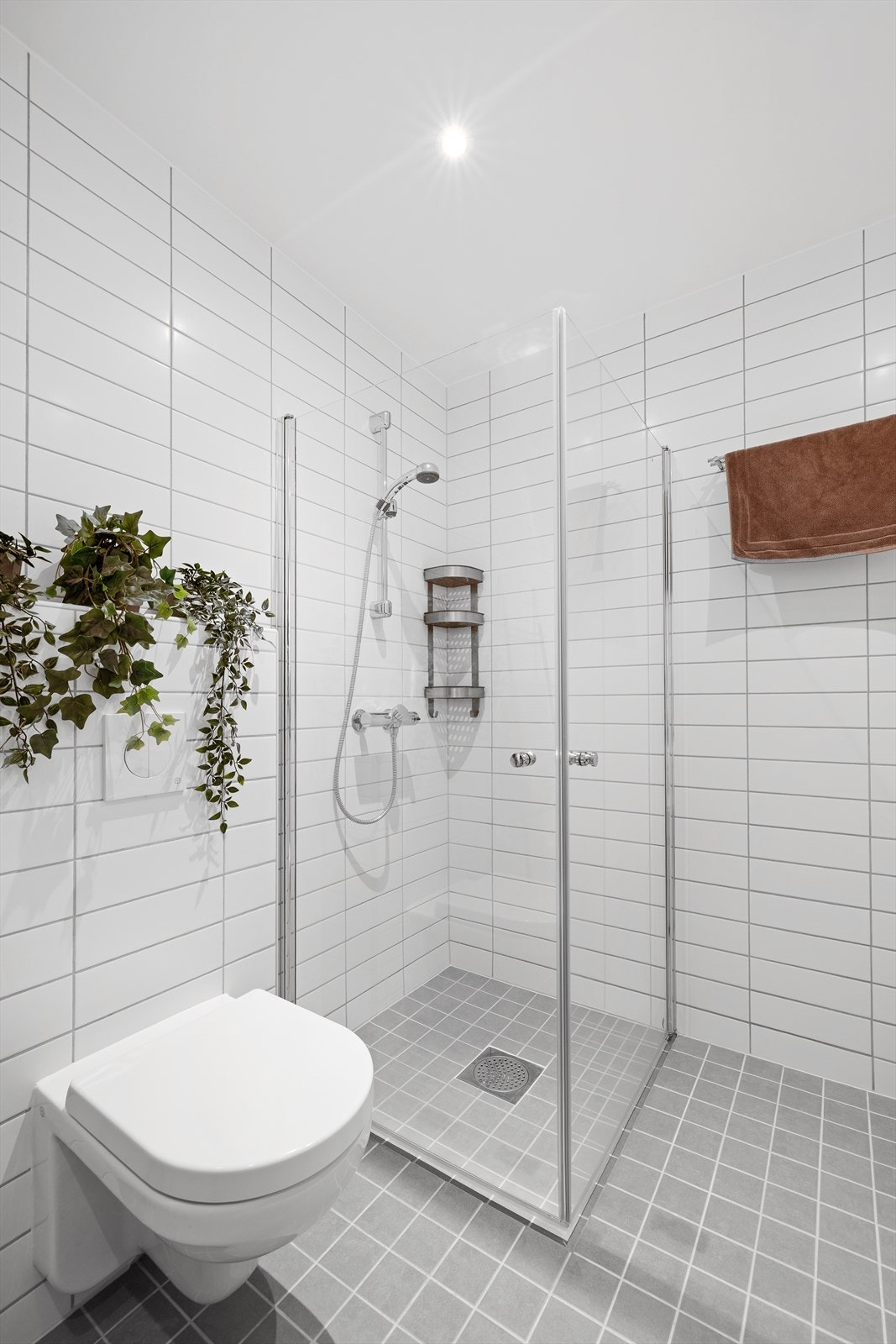 Flislagt bad med dusjhjørne og vegghengt toalett. Galleribilde