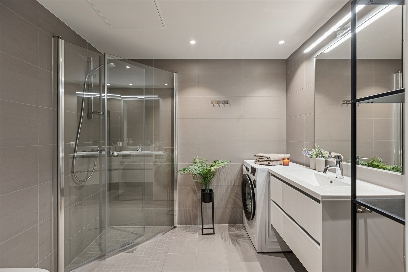 Delikat baderom med lyse fliser i behagelige nyanser og vannbåren gulvvarme. Galleribilde