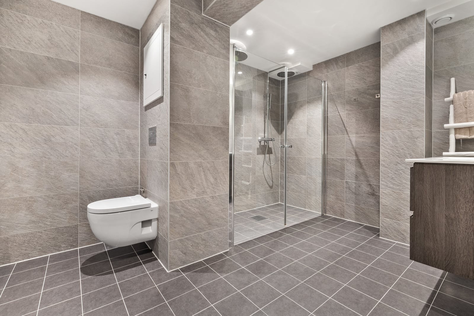 Badet ble rehabilitert i 2022 i regi av borettslaget, og har moderne fliser, vegghengt toalett og en romslig dusjsone. Galleribilde